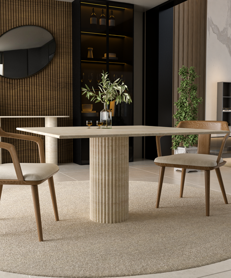 Minimalist scene with a rectangular stone table, two wooden chairs with white cushions, and decorative vases and twigs arranged on the tabletop against a neutral background.