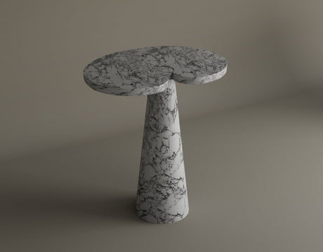 A white marble hourglass-shaped pedestal with grey veining stands against a plain beige background. The surface and base are circular, and the middle section tapers inward.