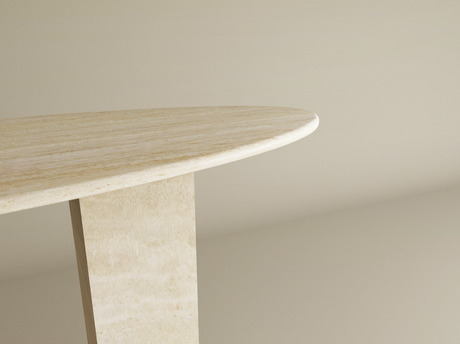 A close-up of the corner of a beige stone or marble table with a rounded edge and a rectangular leg, set against a plain, light-colored background.