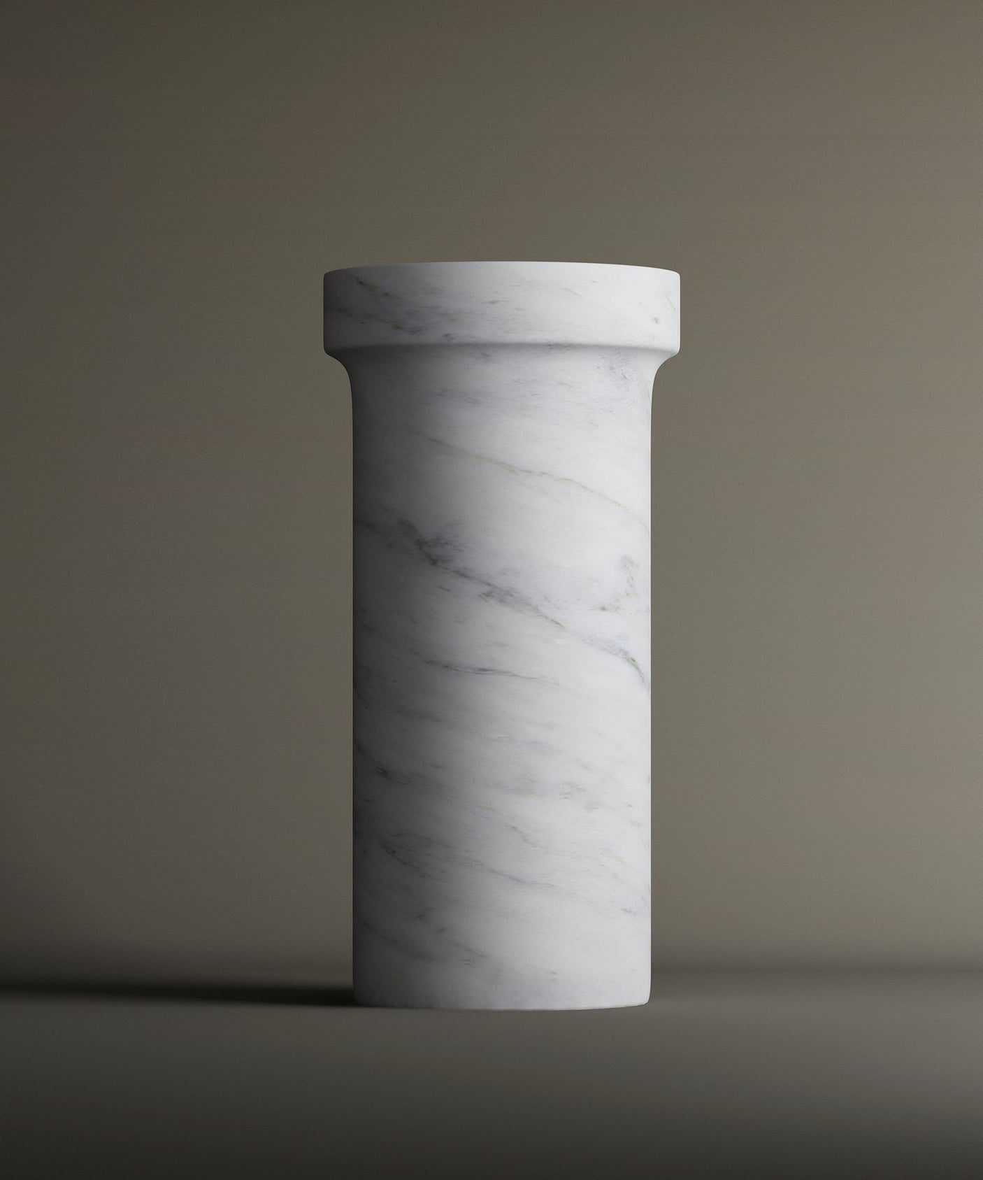 The TRAVERTABLE Carrara Marble Pedestal Vanity Sink features elegant gray veining and a smooth cylindrical design with a wider, flat top—an ideal centerpiece for refined interiors against neutral backgrounds.