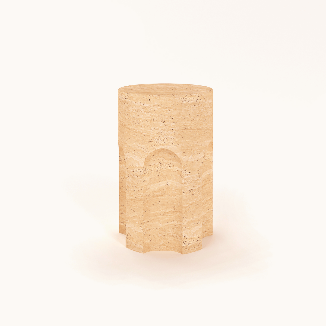 Against a white background, the Travertable Handcrafted Travertine Marble Side Table showcases its cylindrical, polished surface with natural texture and carved arches around its sides in a light beige stone.