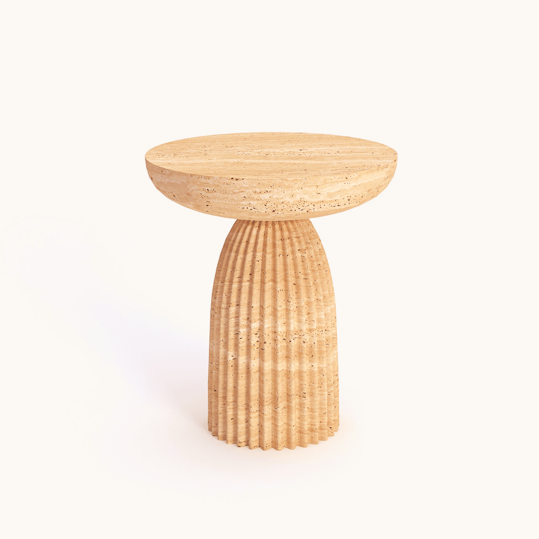 A round side table by Travertable features a textured fluted base and a smooth top, mirroring elegant travertine. Called the Fluted Travertine Side Table, its a hand-carved natural stone accent with a sculptural column base against a plain background.