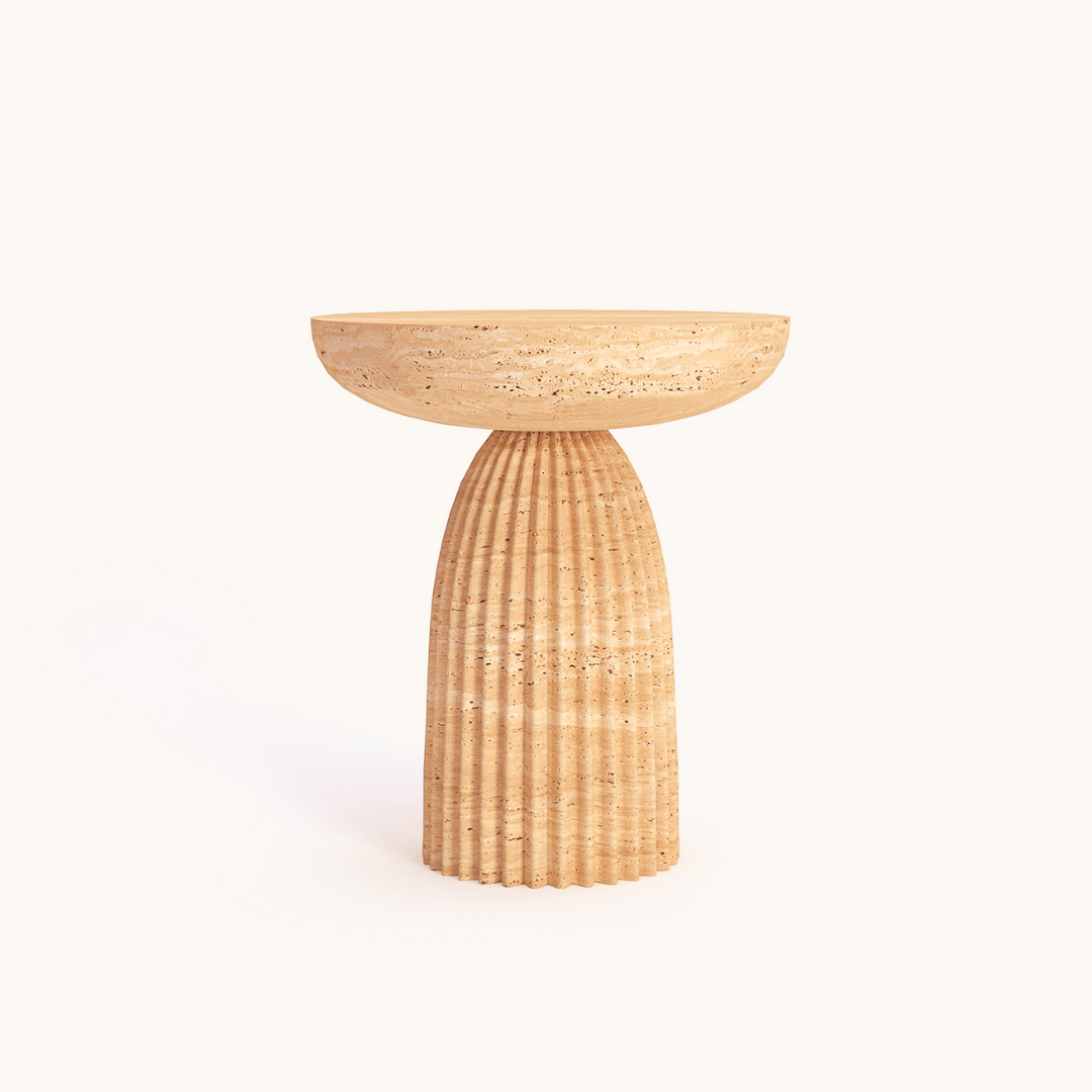 The Fluted Travertine Side Table by Travertable features a hand-carved natural stone design with a ribbed column base and smooth, bowl-shaped top on a tan pedestal, set against a plain white background.