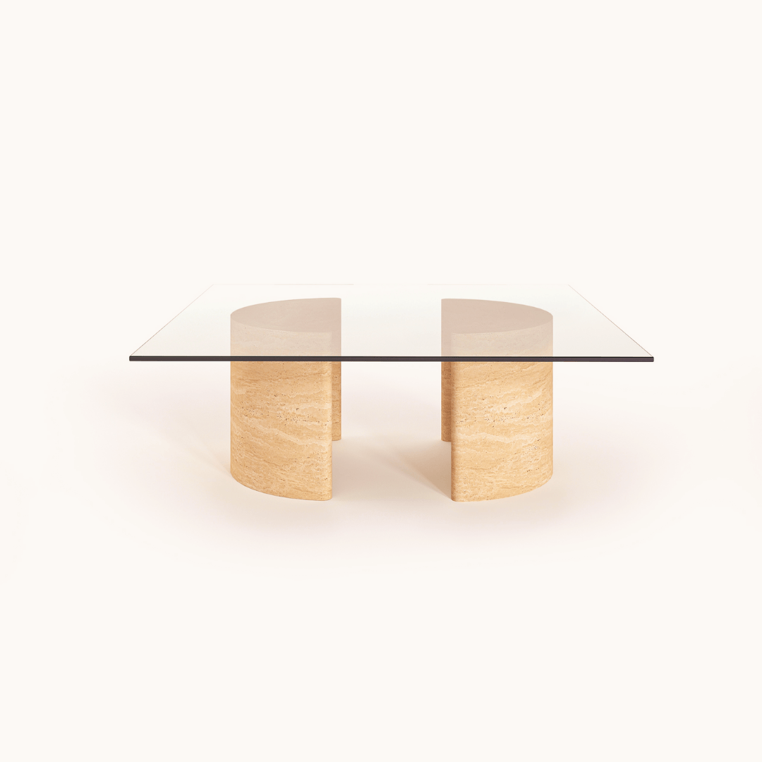 Introducing the Travertable Stone Horizon Coffee Table, a hand-sculpted masterpiece. This modern piece has a transparent glass top supported by dual semi-cylindrical beige stone bases, exuding natural beauty against its plain white background. Perfect for both modern and rustic interiors.