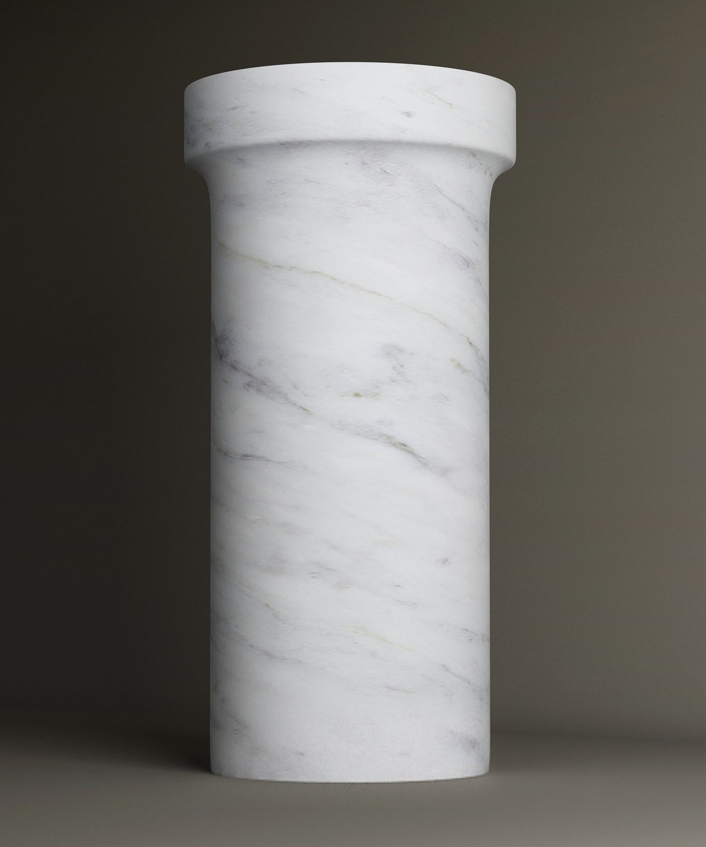 The TRAVERTABLE Carrara Marble Pedestal Vanity Sink features a tall, cylindrical design crafted from white Carrara marble with subtle grey veining, showcased upright against a plain, neutral background.