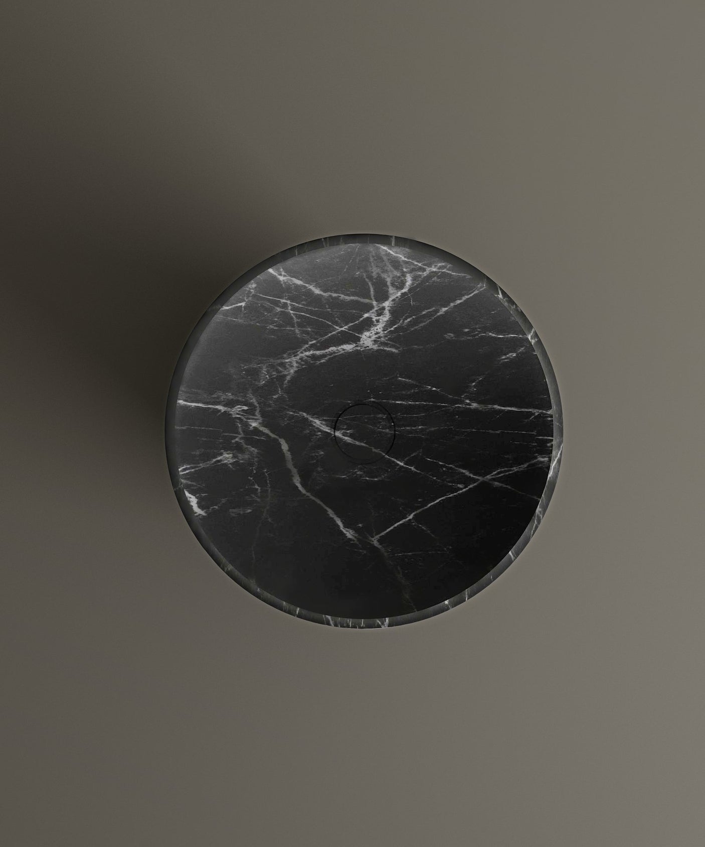 The TRAVERTABLE Nero Marquina Marble Cylinder Pedestal Vanity Sink features a round top with signature white veining and a subtle circular center marking, all shown from above against a plain gray background for a modern, sculptural look.