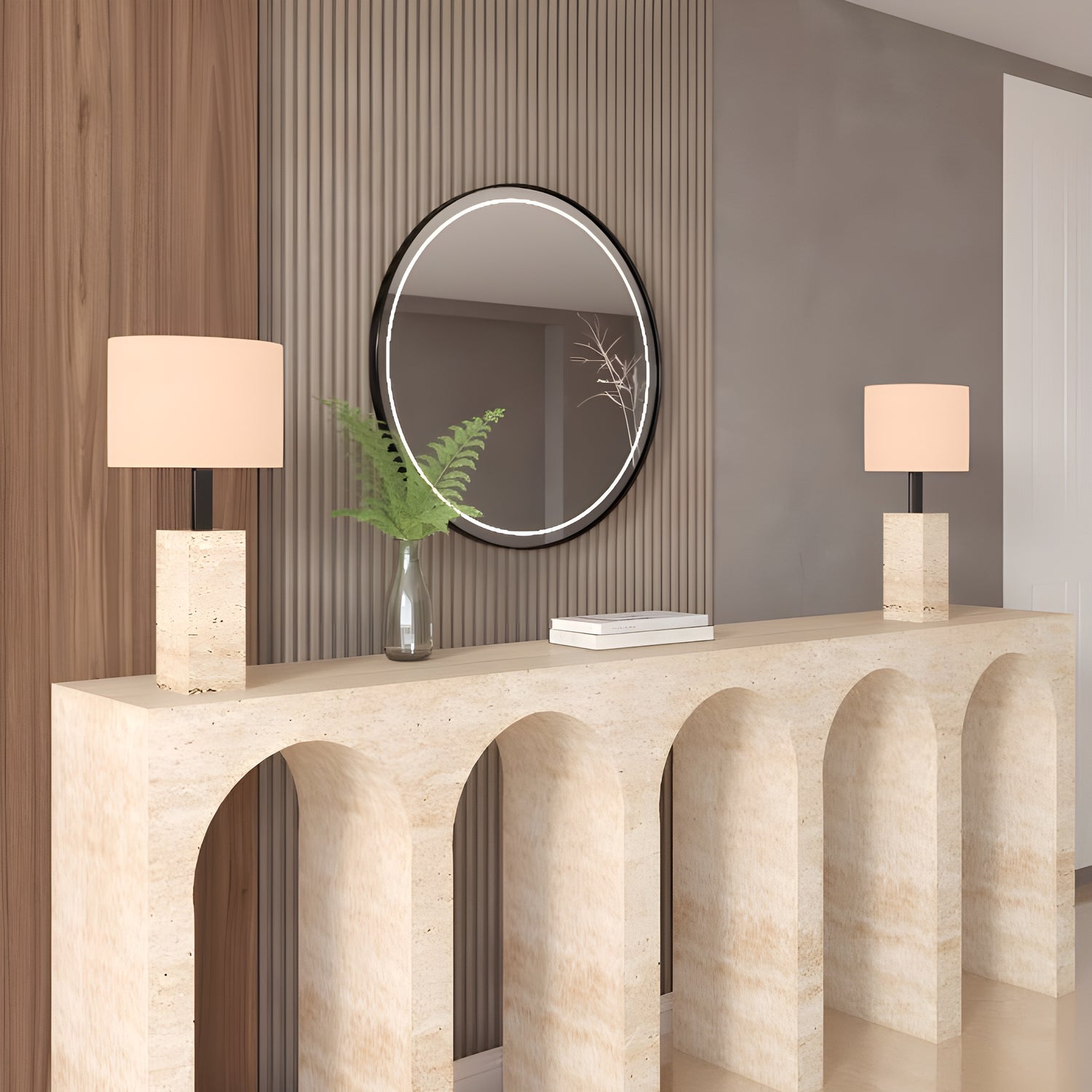 A modern entryway exudes understated luxury with the TRAVERTABLE Travertine Console Table with Five Arches, two white-shaded lamps, a round mirror above, and a glass vase of green fern leaves.