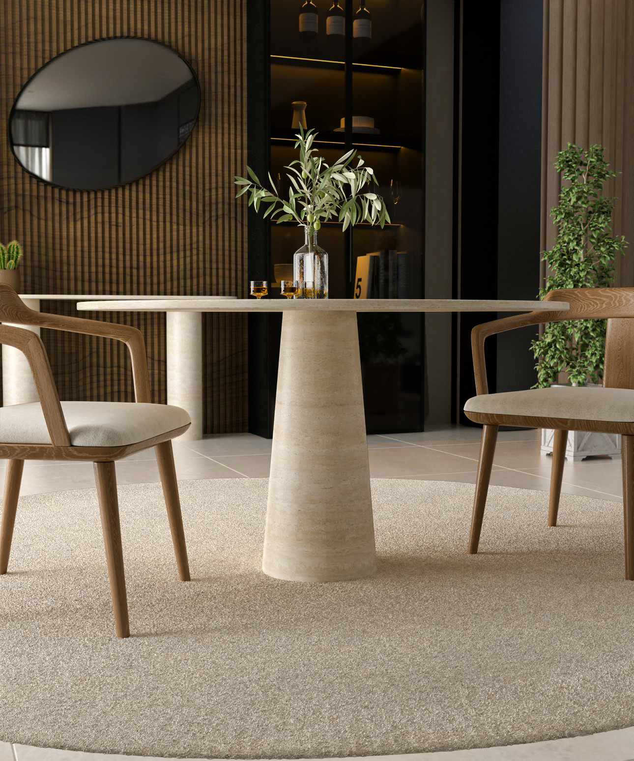 The TRAVERTABLE Oval Travertine Dining Table with Conical Center Base in natural stone is styled with a glass bottle, glasses, and a leafy vase. Two wooden chairs sit on a circular rug in a modern, neutral-toned room.