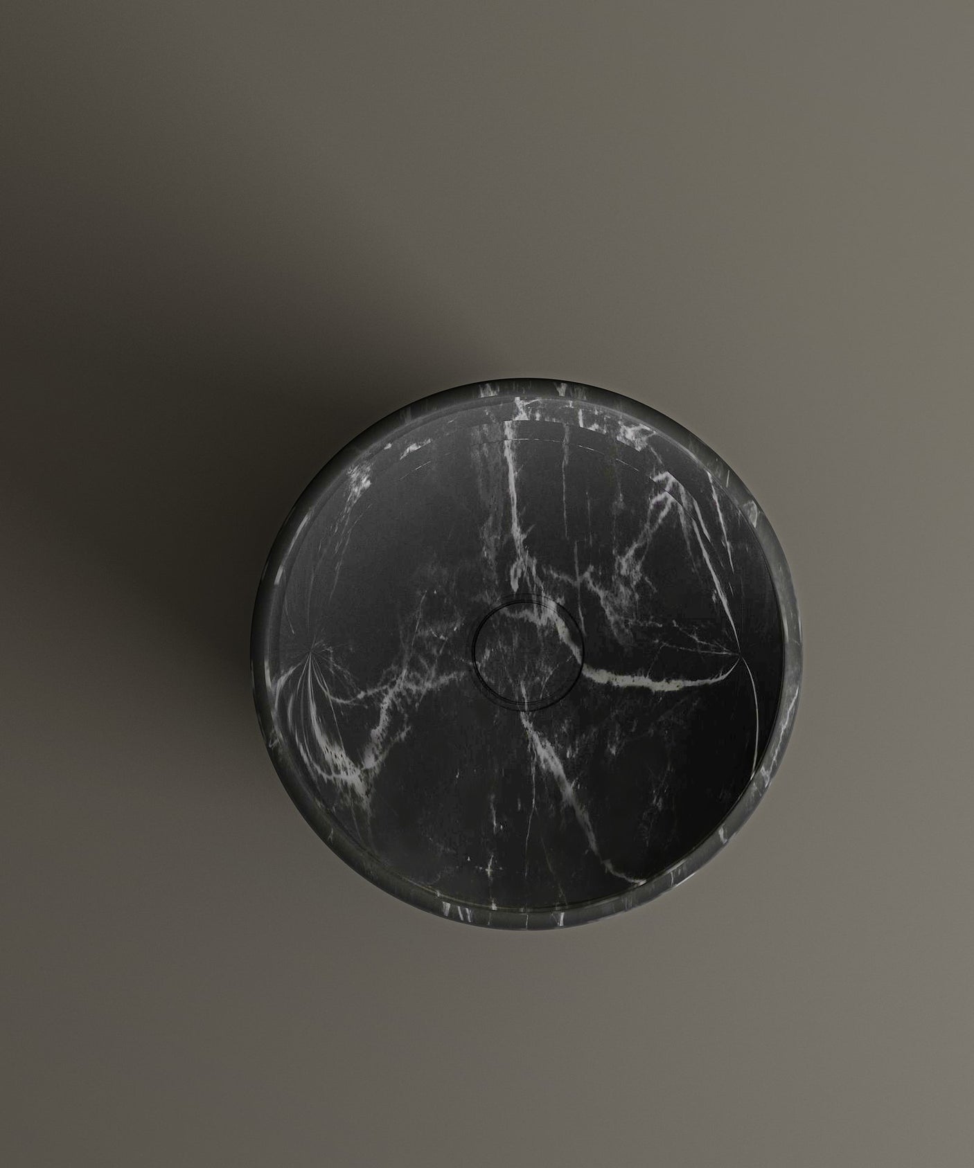 The TRAVERTABLE Nero Marquina Marble Pedestal Vanity Sink features bold white veining and a round design, mounted on a matte brown wall—an elegant focal point for modern interiors. Captured from above, its central drain ensures both style and function.