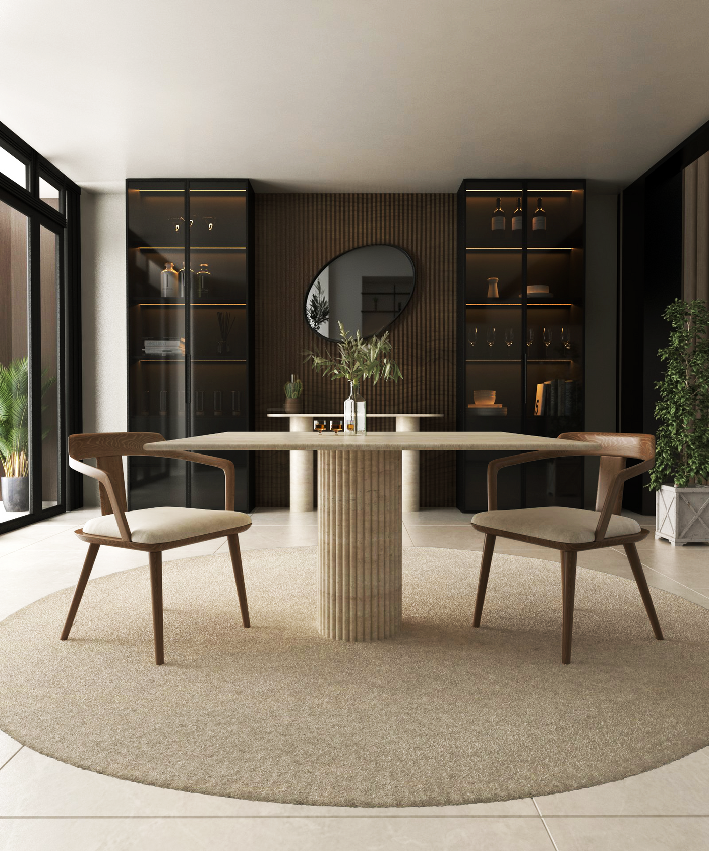 A modern dining room featuring the TRAVERTABLE Square Travertine Dining Table with a fluted round base, two wooden chairs, a beige circular rug, glass-front cabinets, a round mirror on a wood accent wall, and potted plants by large windows.