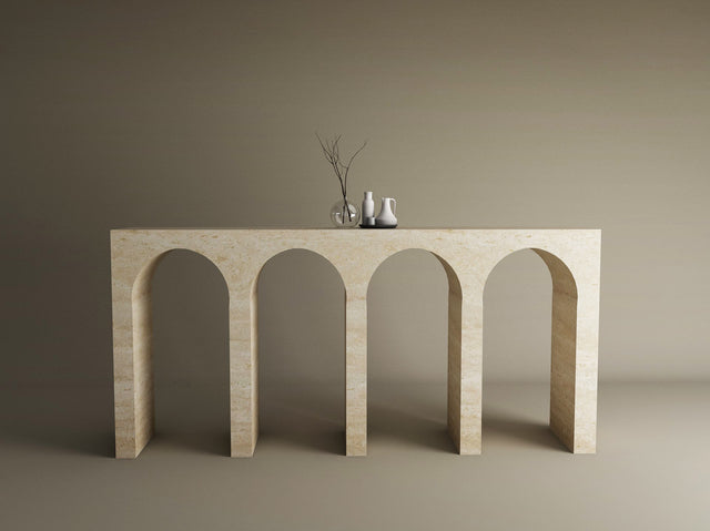 The TRAVERTABLE Travertine Console Table with Four Arches stands against a beige wall, highlighting sculptural elegance. Three minimalist decor pieces on top complete this refined display of the customizable Architectural Stone Console.