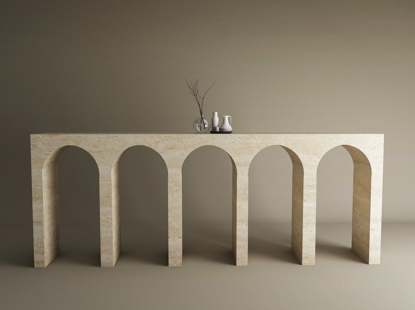 The TRAVERTABLE Travertine Console Table with Five Arches stands against a brown wall, topped with three white vases and a glass vase of bare branches—a customizable, sculptural masterpiece of understated luxury.