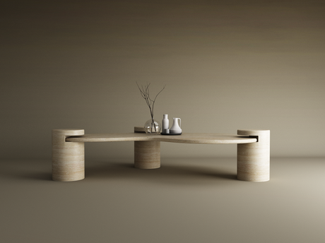 The Wavy Travertine Coffee Table with Cylindrical Base by TRAVERTABLE features sculptural curves and three legs, topped with a round glass vase of bare branches, a white pitcher, and a light gray vase against a brown gradient background.