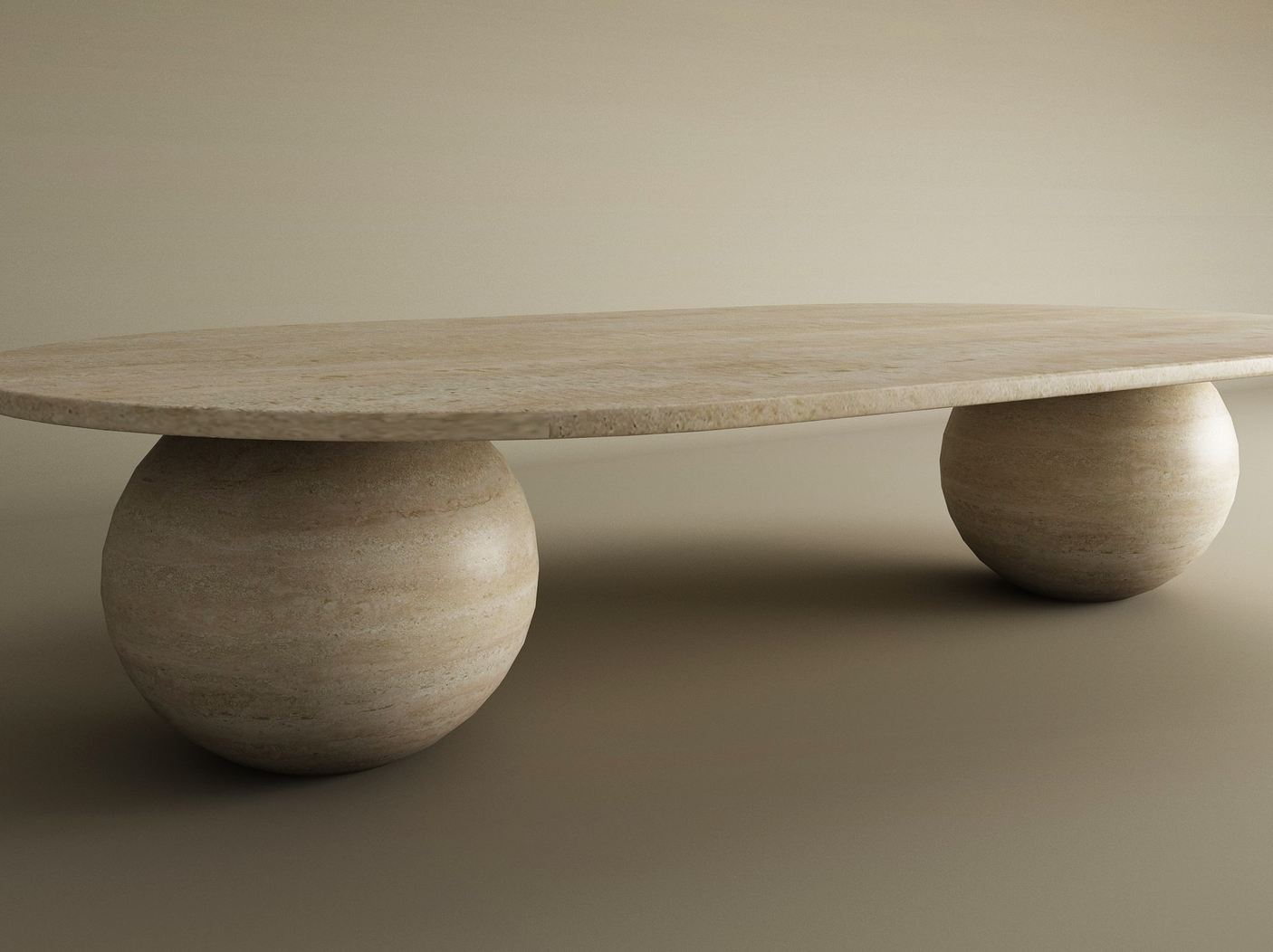 The TRAVERTABLE Oval Travertine Coffee Table with Stone Ball Base features a modern, minimalistic design in earthy tones. Crafted by Artistic Travertine, it offers smooth textures and customizable options against a plain neutral background.