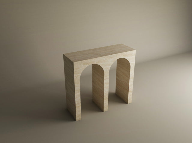 The TRAVERTABLE Travertine Console Table features a solid stone build and two arch-shaped legs, creating a customizable statement piece that showcases minimalist geometric design in a softly lit, neutral space.