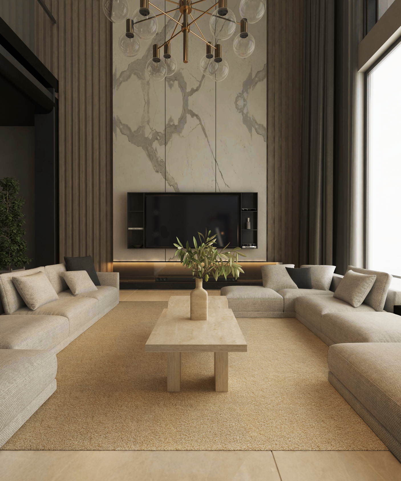 A modern living room showcases beige U-shaped sectional sofas around the TRAVERTABLE Architectural Travertine Coffee Table with Sculptural Base. A natural stone wall with a mounted TV, shelves, tall gray curtains, windows, and a gold chandelier complete the organic design.