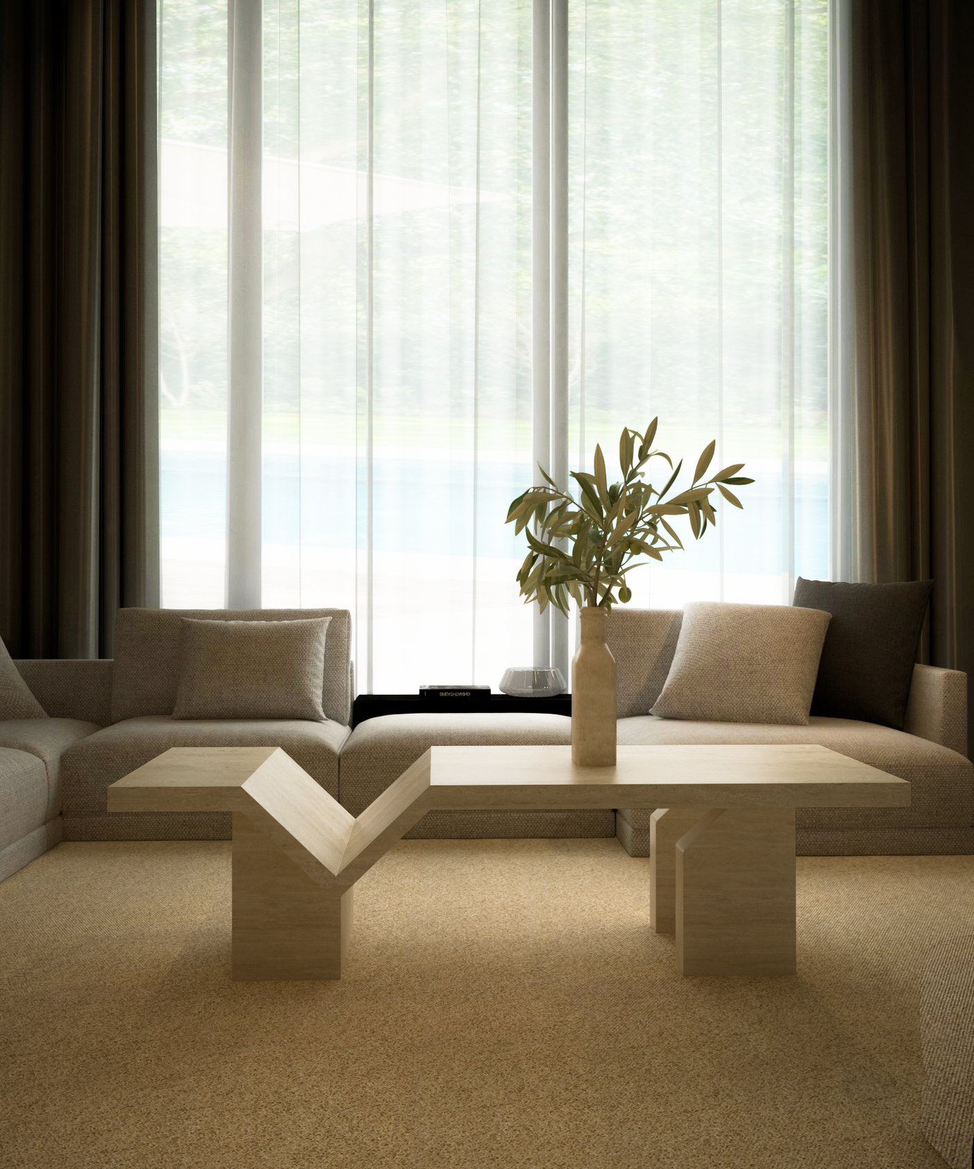 A modern living room features a beige sectional, a TRAVERTABLE Architectural Travertine Coffee Table with Sculptural Base, and a tan vase with green branches. Sheer white curtains and brown drapes on floor-to-ceiling windows fill the space with natural light.