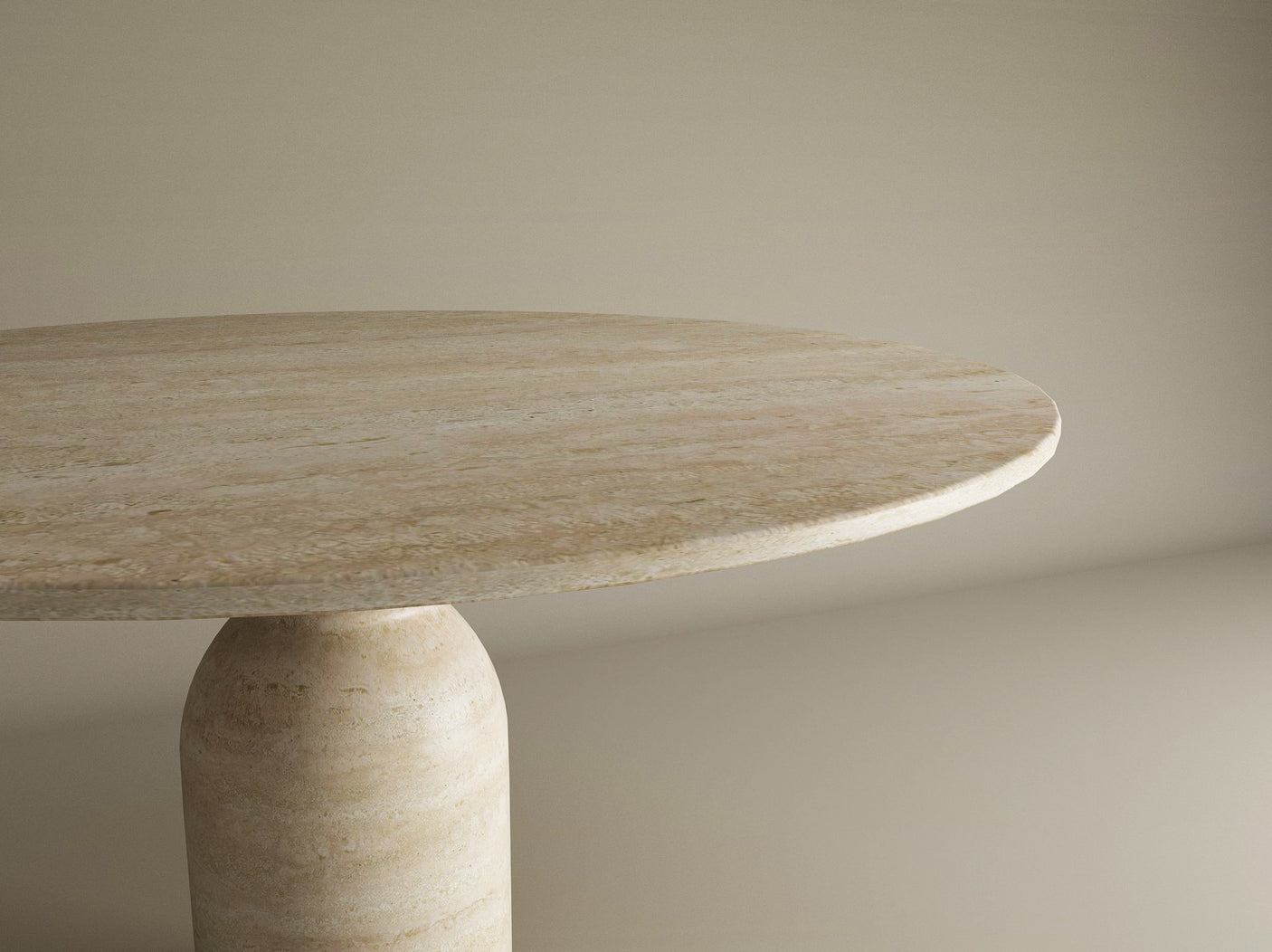 A close-up view of the TRAVERTABLE Oval Travertine Dining Table with a round sculptural center base. The polished, light beige surface features natural stone patterns, highlighting this customizable, organic travertine form against a neutral backdrop.