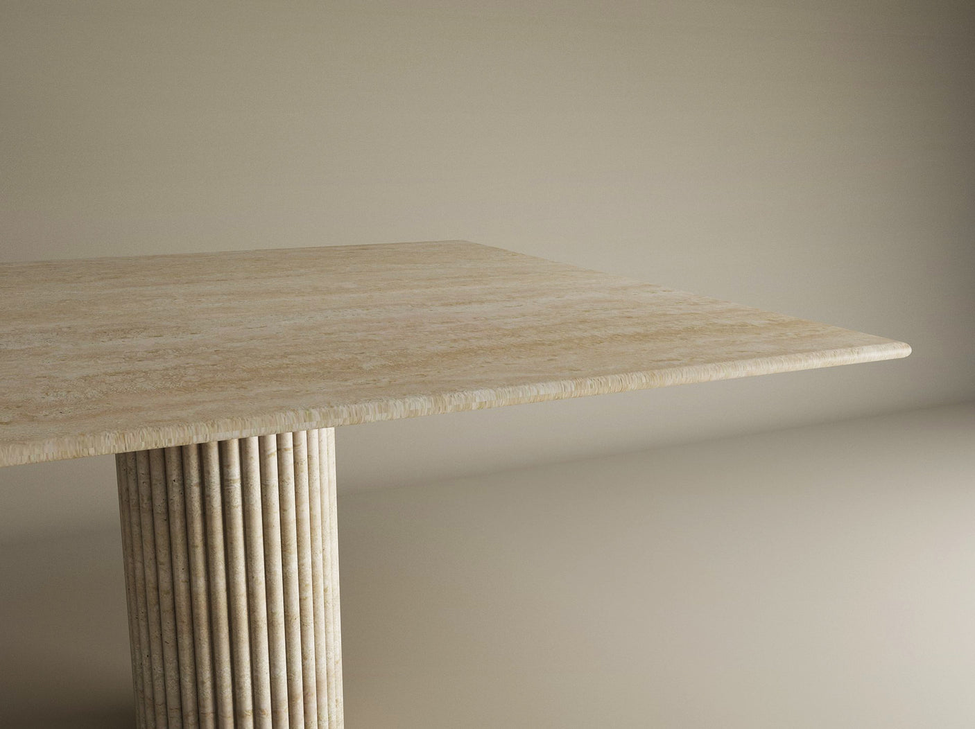 A close-up of the Square Travertine Dining Table by TRAVERTABLE shows one corner and its natural stone top, featuring a fluted round center base, set against a neutral backdrop.