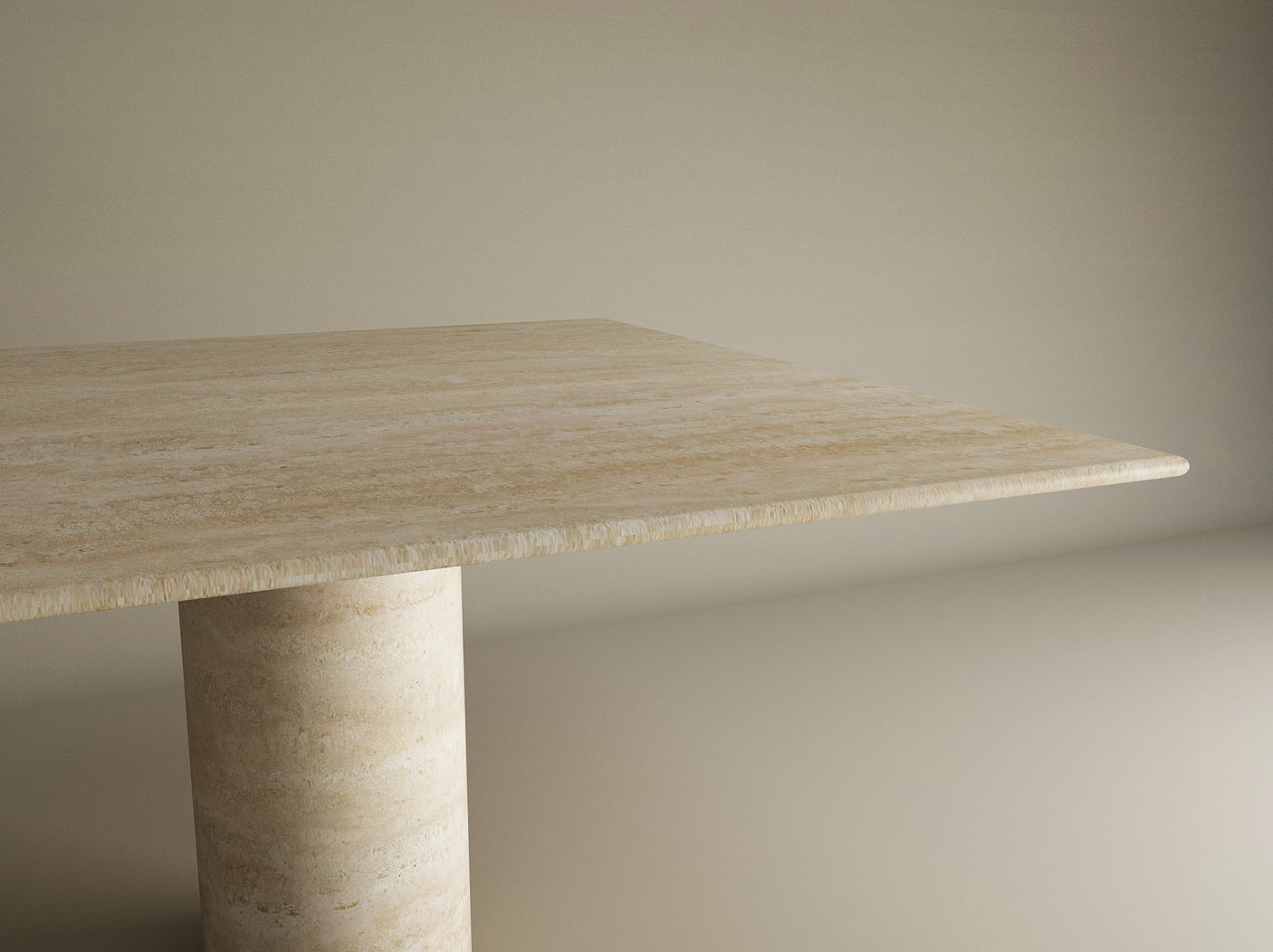 A close-up of the TRAVERTABLE Square Travertine Dining Table, featuring pure travertine stone with natural veining and a cylindrical center base, set against a plain beige background. Customizable design.