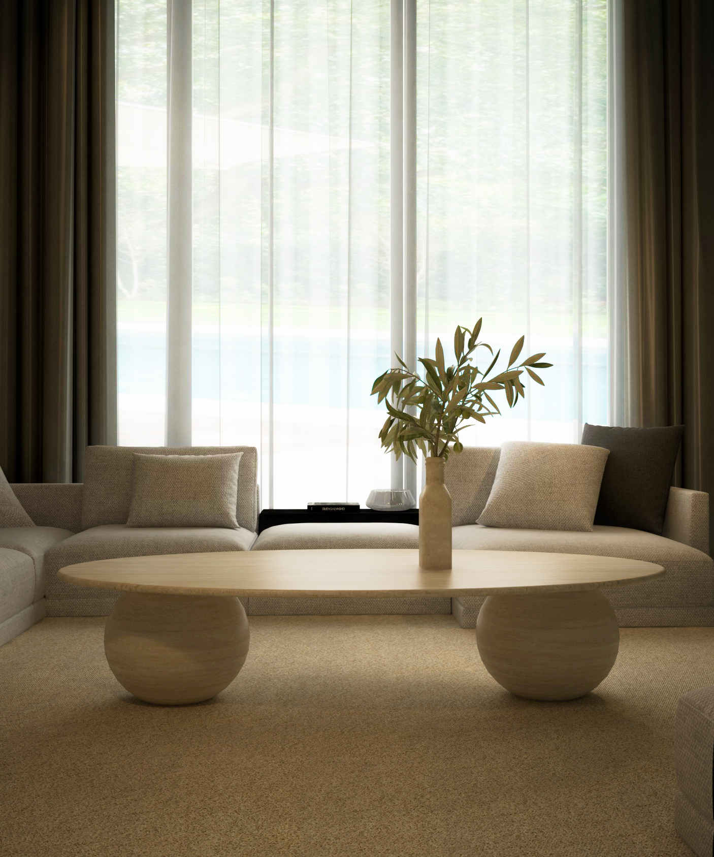 A modern living room featuring TRAVERTABLEs customizable Ellipse Travertine Coffee Table with a sculptural stone ball base, a vase of leafy branches, two cream sofas with neutral cushions, and sheer curtains over a tall window with an outdoor view.