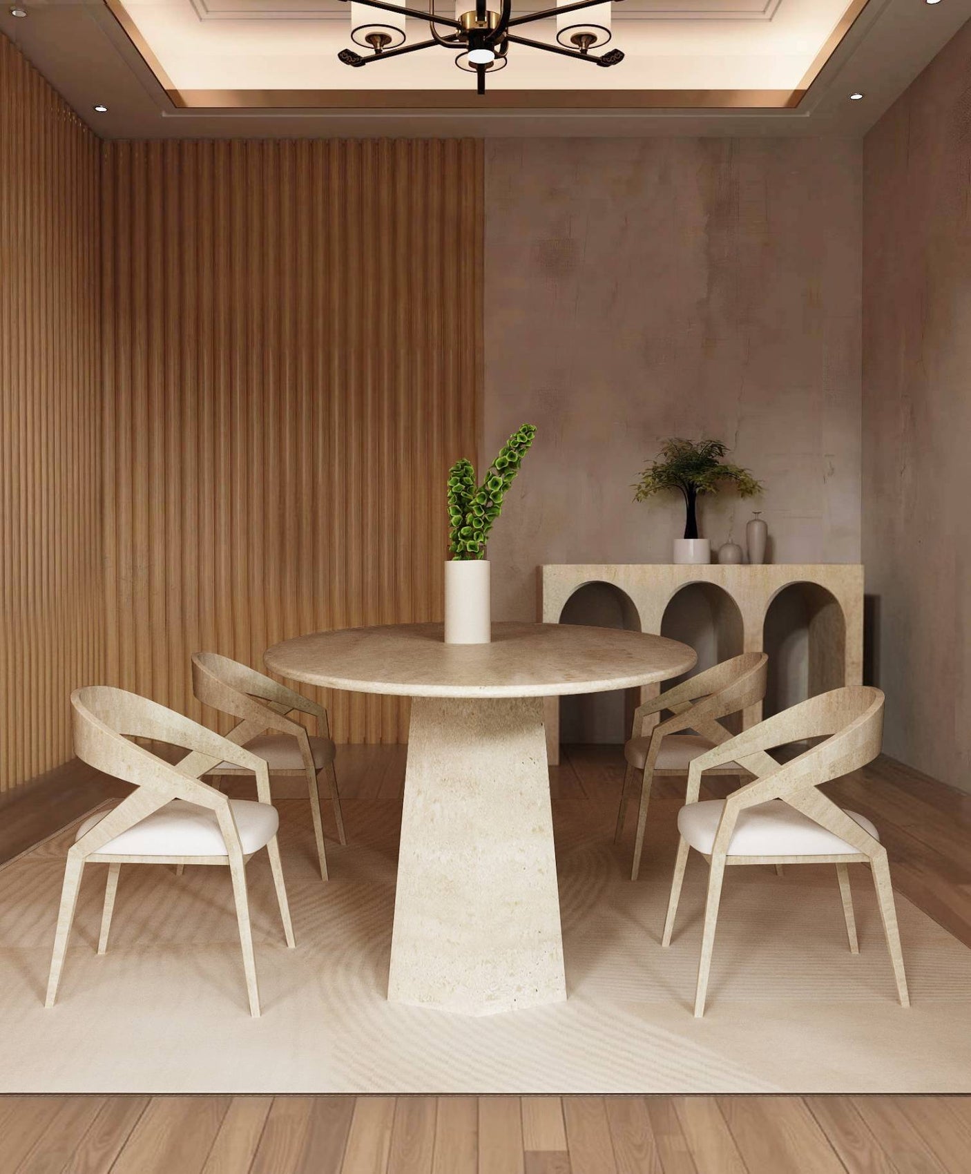A modern dining area with a TRAVERTABLE Ellips Travertine Dining Table featuring a solid stone base, four beige chairs, a vase with green leaves, sideboard decor, wood flooring, textured beige walls, and a chandelier overhead.