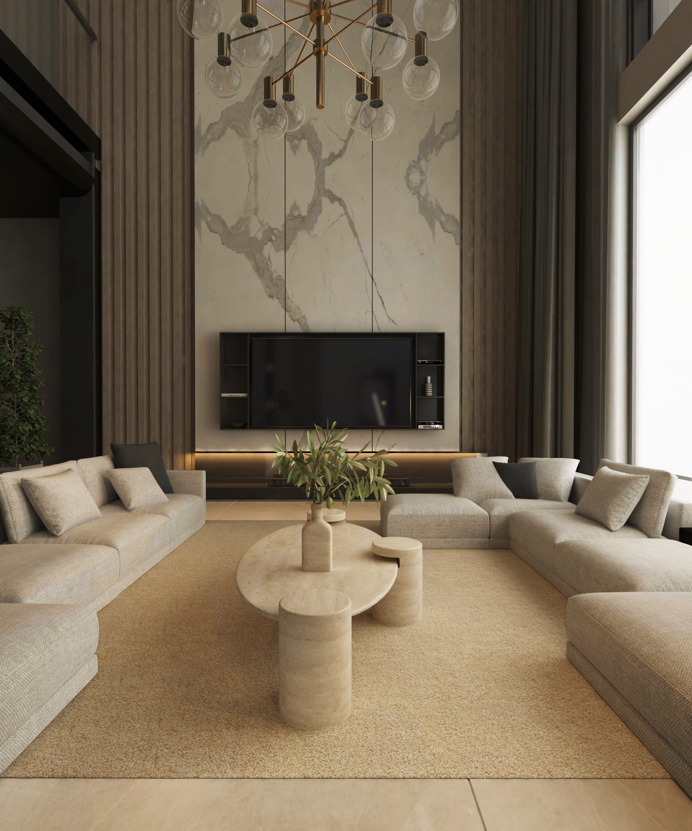 A modern living room with L-shaped beige sofas around the TRAVERTABLE Ellipse Travertine Coffee Table featuring a cylindrical base and soft organic form, a beige rug, marble accent wall with TV, large curtained window, and gold chandelier.