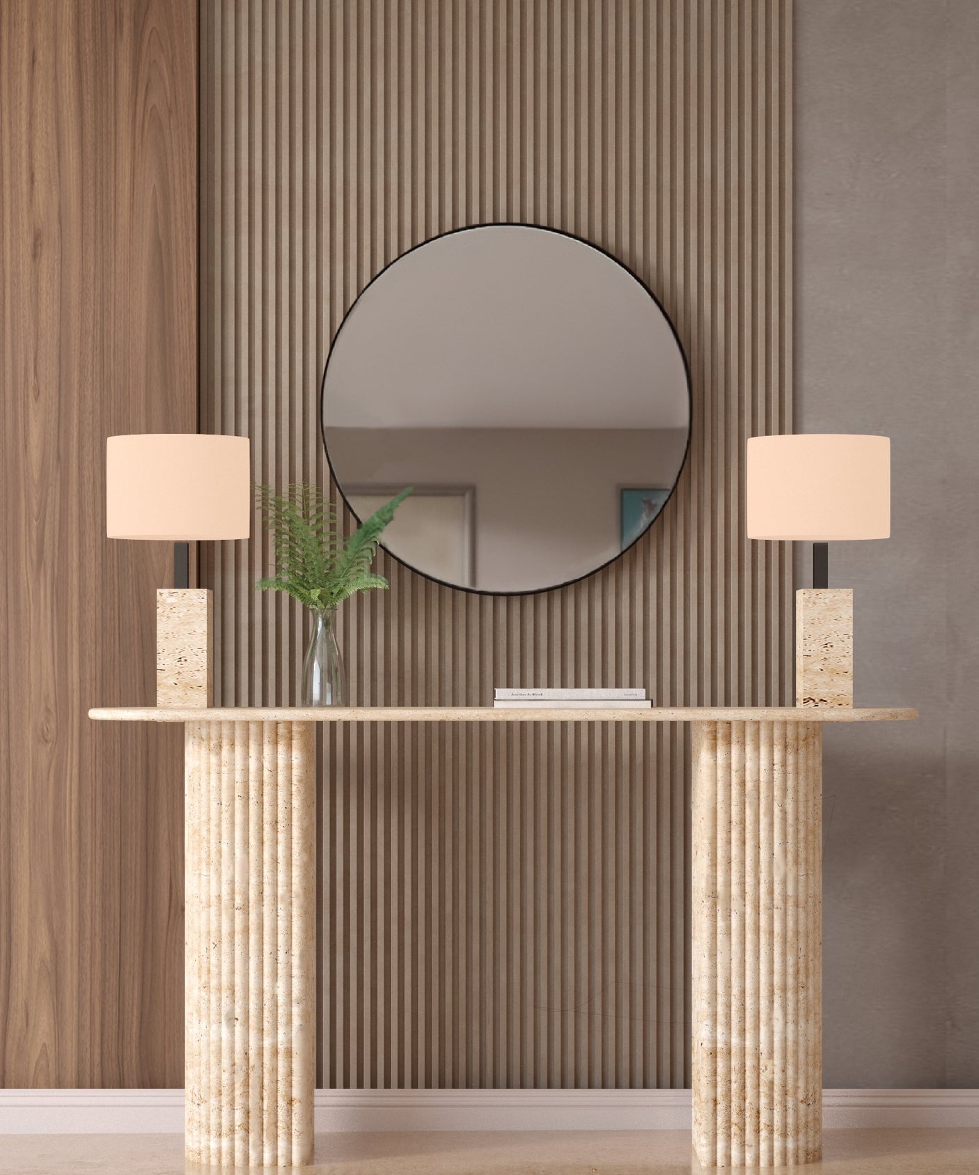The TRAVERTABLE Ellips Travertine Console Table with Fluted Round Base, paired with two beige lamps and a glass vase of green leaves, stands against vertical wooden panels beneath a round mirror reflecting refined luxury.