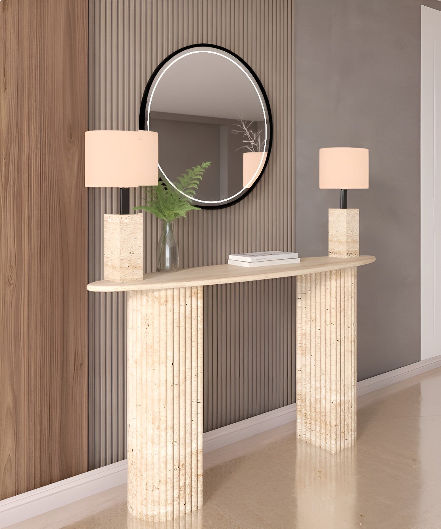 The TRAVERTABLE Ellips Travertine Console Table with Fluted Round Base displays two square lamps and a glass vase with greenery beneath a round mirror, bringing refined luxury to wood and gray paneled walls.