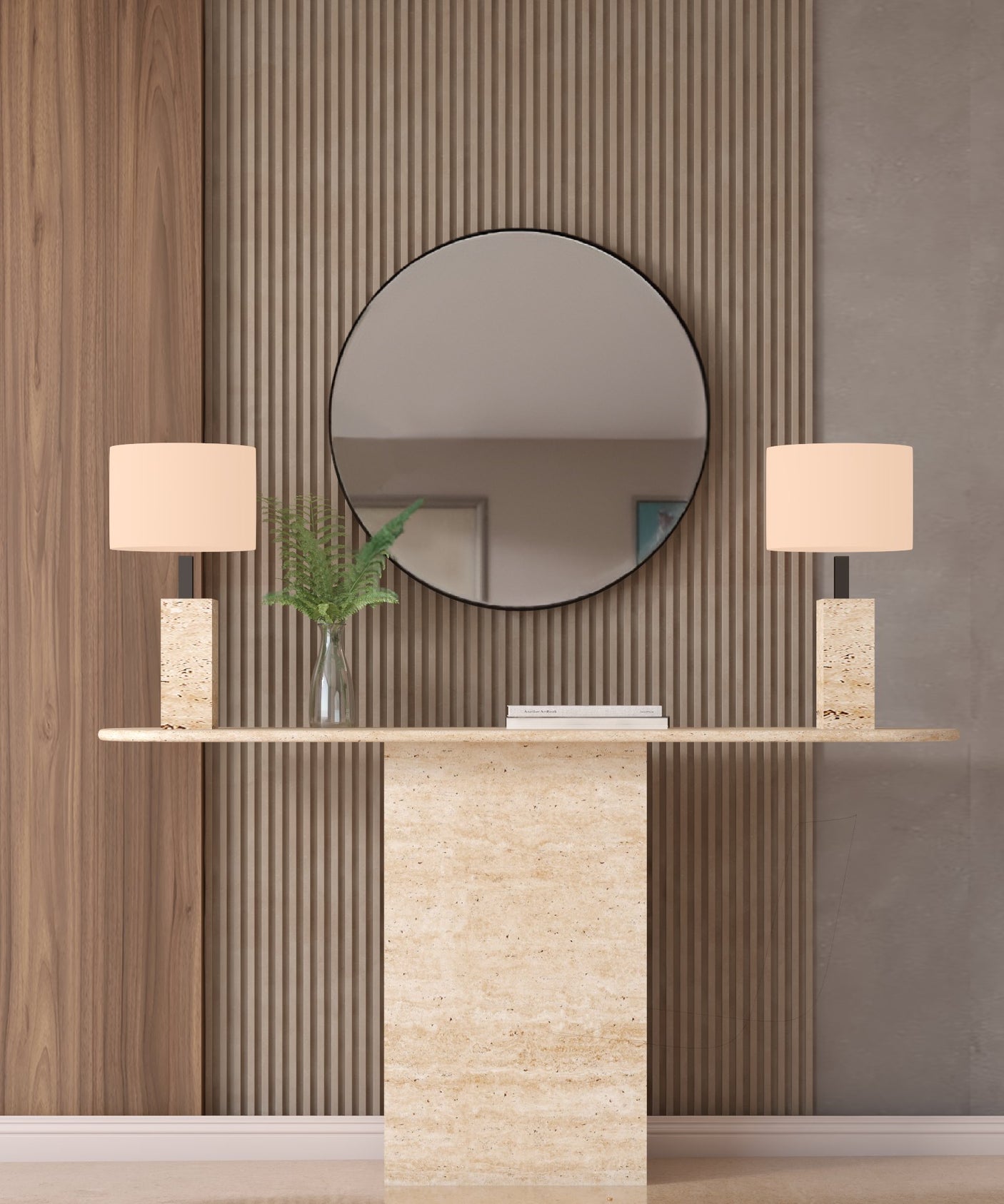 A TRAVERTABLE Ellips Travertine Console Table with Block Base in natural stone stands beneath a large round mirror, flanked by two matching lamps and a glass vase with green leaves, while a closed book rests between the lamps.