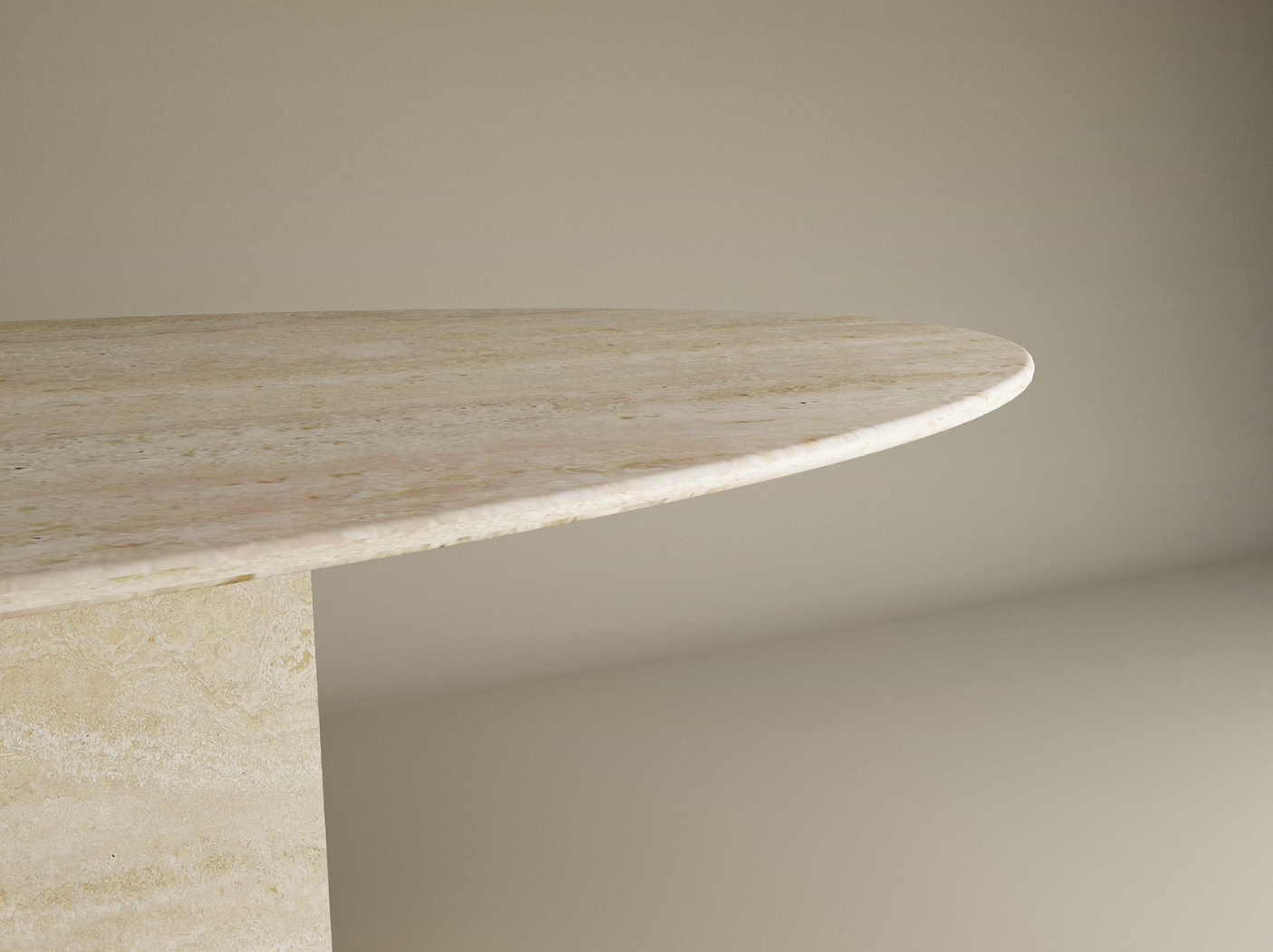 A close-up of the TRAVERTABLE Ellips Travertine Dining Table’s smooth natural stone edge and block base, set against a neutral backdrop. Only part of this customizable heirloom piece is visible.