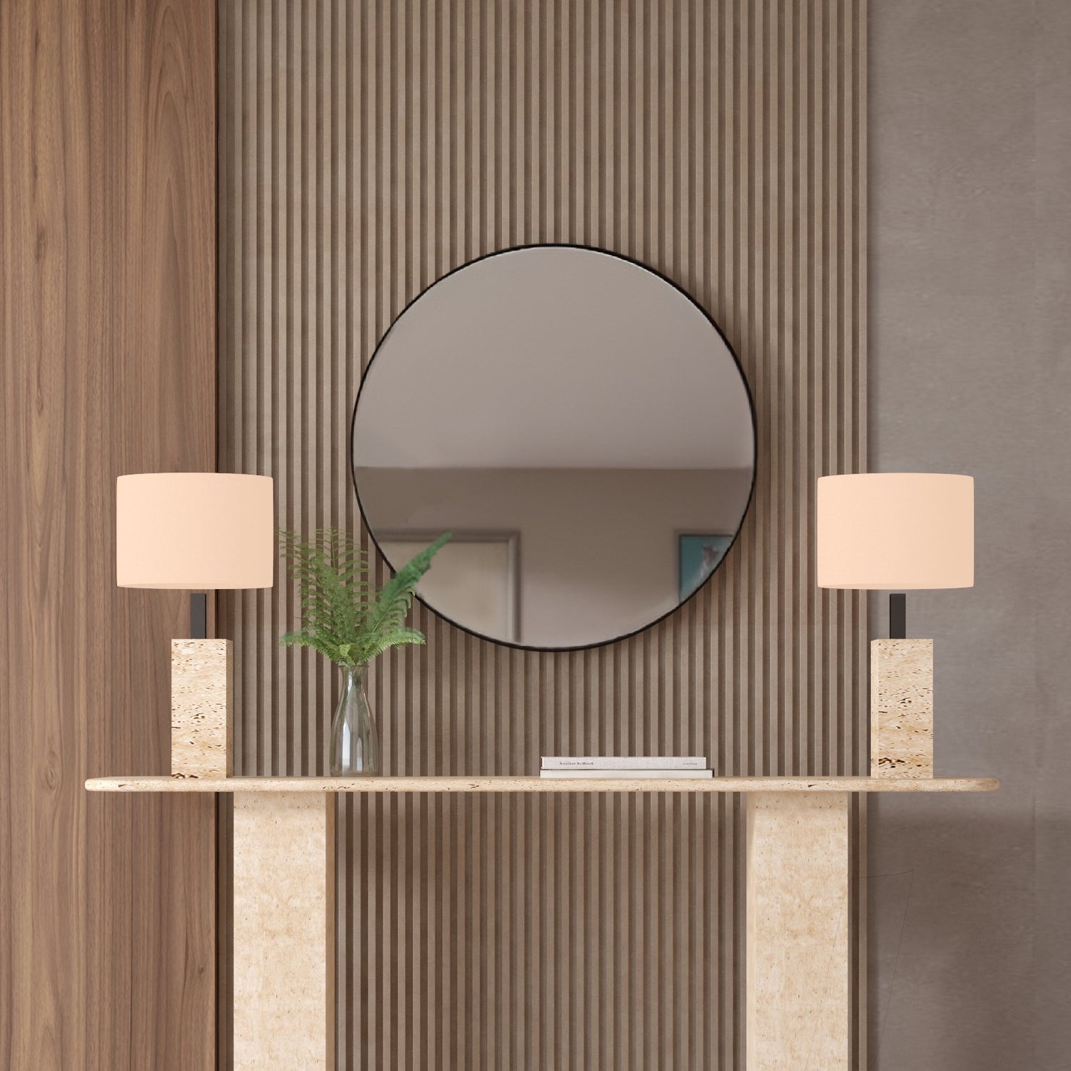 A TRAVERTABLE Rectangular Travertine Console Table with a travertine stone base displays two rectangular-based lamps, a glass vase with green ferns, and stacked books. A round mirror hangs on a wall of vertical wooden slats behind it.