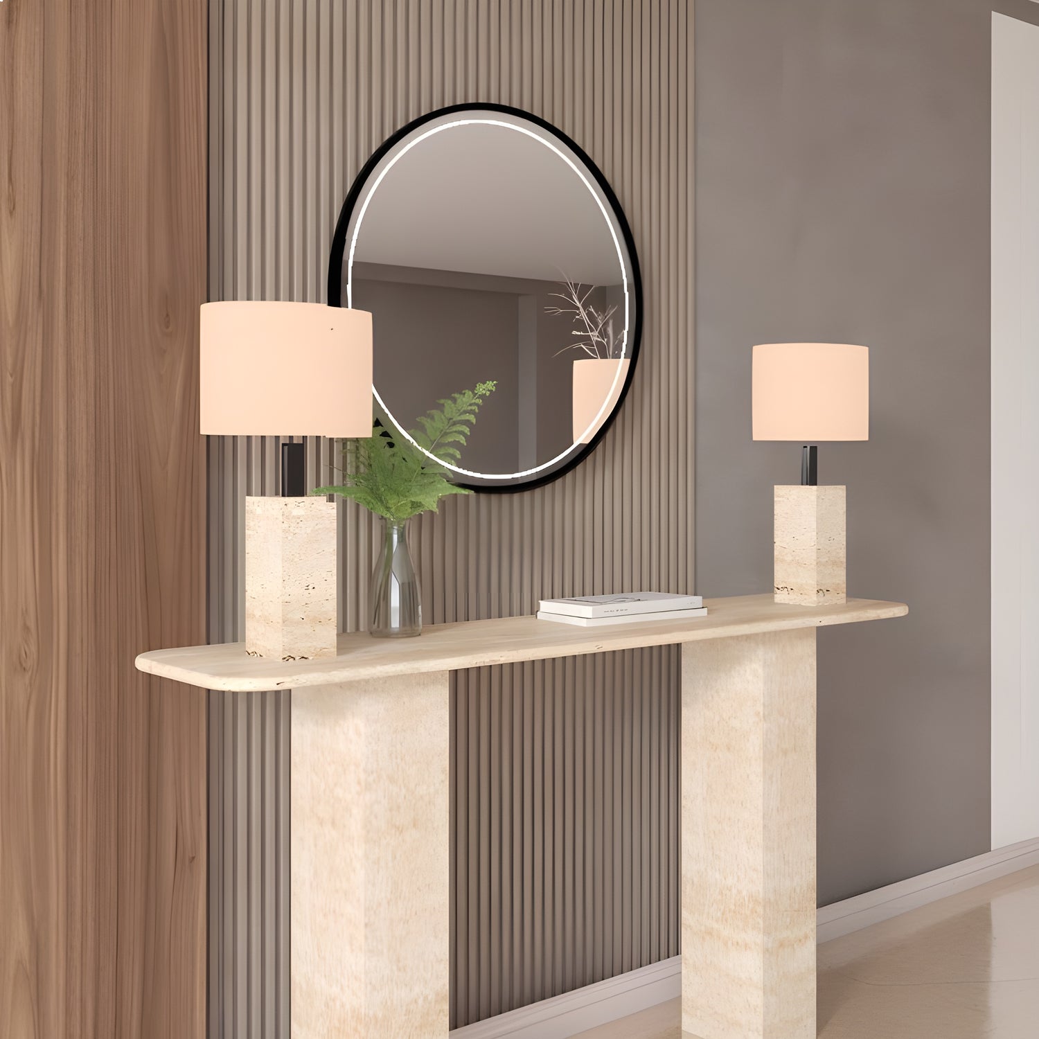The TRAVERTABLE Rectangular Travertine Console Table with Pedestal Base displays two square lamps and a glass vase of greenery, set below a round mirror on a backdrop of vertical wood paneling.