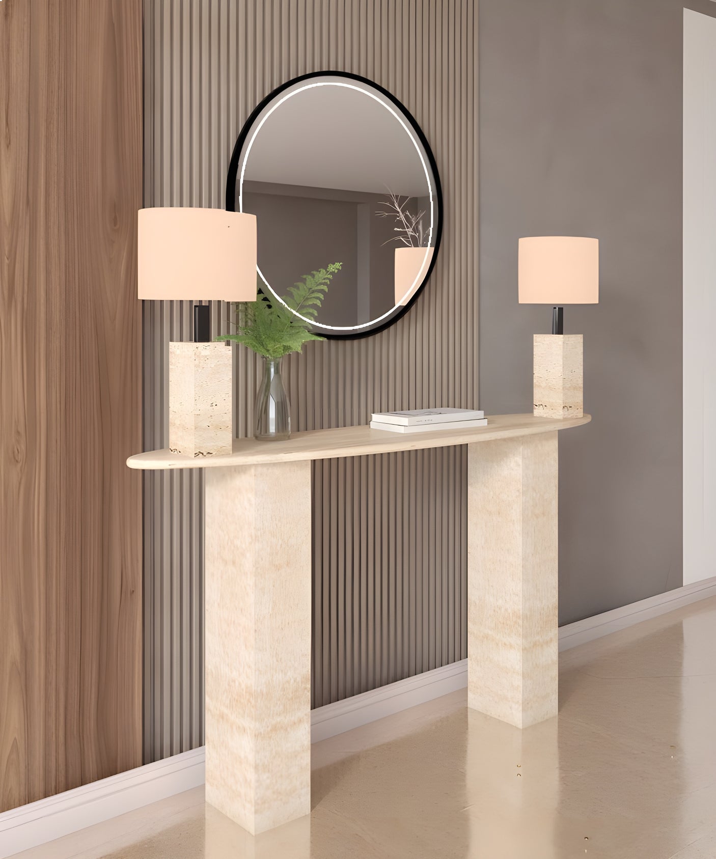 The TRAVERTABLE Ellips Travertine Console Table with a rectangular pedestal base stands against light wood and gray paneling, paired with two square lamps, a glass vase of greenery, and topped by a round black-framed mirror.
