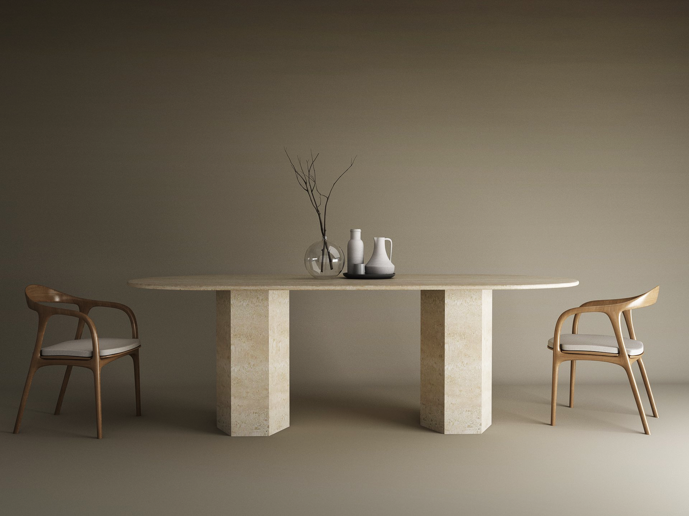 A minimal dining setup features the TRAVERTABLE Oval Travertine Dining Table with a hexagonal stone base, two wooden chairs with white cushions, three ceramic vessels, and a glass vase with branches, all set against a plain brown background.