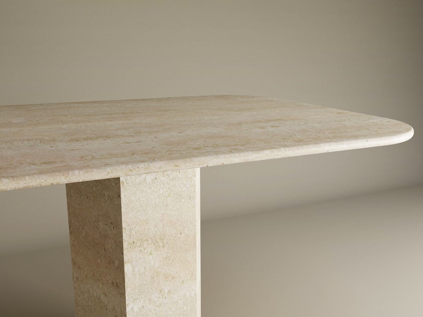 A close-up of the TRAVERTABLE Rectangular Travertine Dining Table, featuring a minimalist light-colored top, rounded edges, and an organic hexagonal stone pedestal base, set against a neutral beige background.