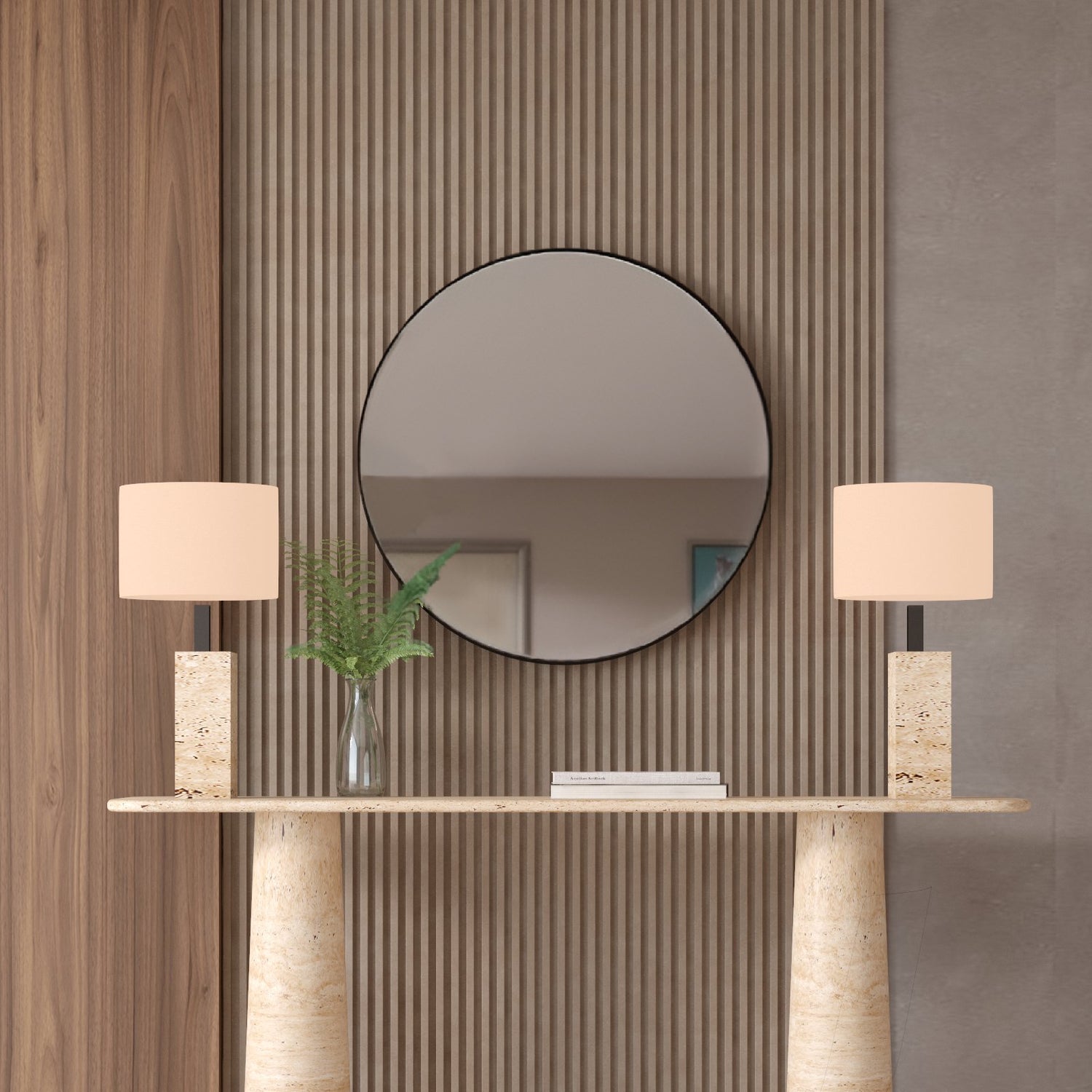 A modern entryway features a round mirror on a ribbed wood wall, the TRAVERTABLE Ovale Travertine Console Table with conical pedestal base, two beige rectangular-shade lamps, and a glass vase filled with green fern leaves.