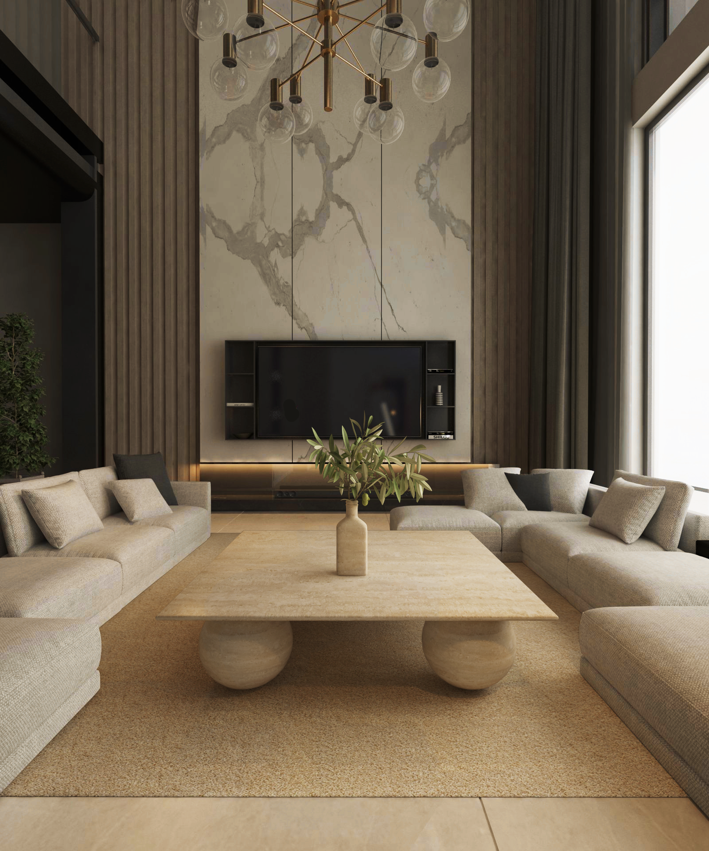 A modern living room showcases a marble wall, mounted TV, and long beige sofas around the TRAVERTABLE Square Travertine Coffee Table with Stone Ball Base. A minimal vase with greenery, tall windows, and a gold chandelier complete the elegant space.
