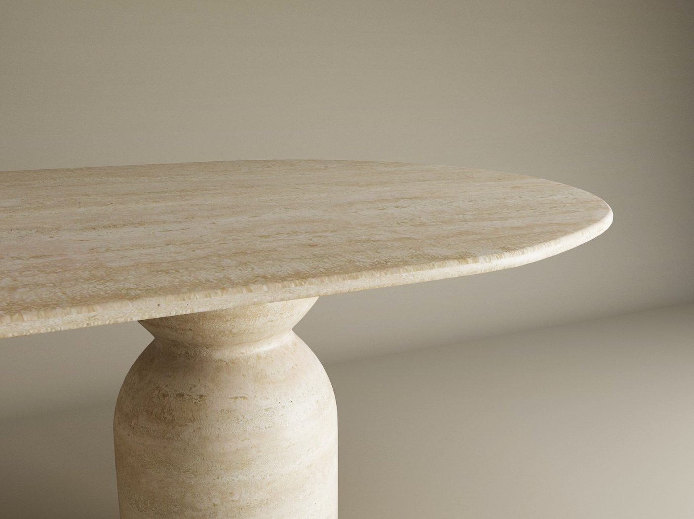 A close-up of the TRAVERTABLE Oval Travertine Dining Table, featuring an organic stone tabletop and sculptural round base, set against a plain, light-colored background. Customizable design.