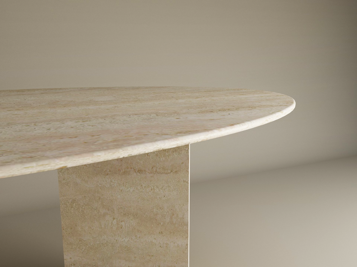 A close-up of the TRAVERTABLE Ellips Travertine Dining Table, featuring a minimalist oval top and a split-V travertine stone pedestal base, set against a neutral light background. Customizable options available.
