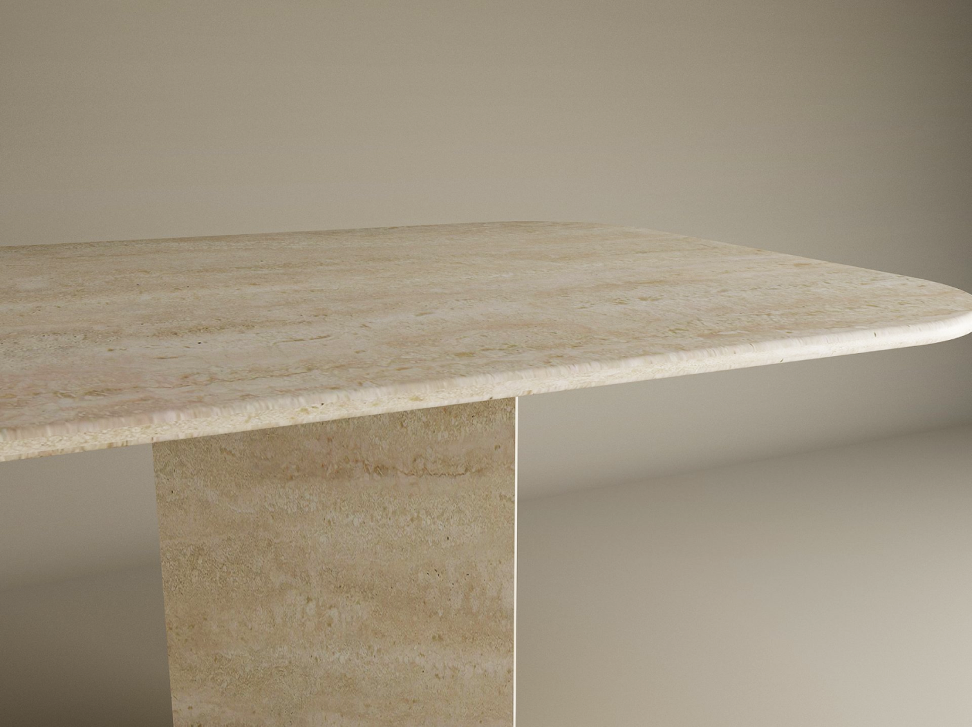 A close-up of the TRAVERTABLE Rectangular Travertine Dining Table, featuring a beige natural stone top with rounded edges and a split-V travertine stone pedestal base, set against a plain light background. Customizable design.