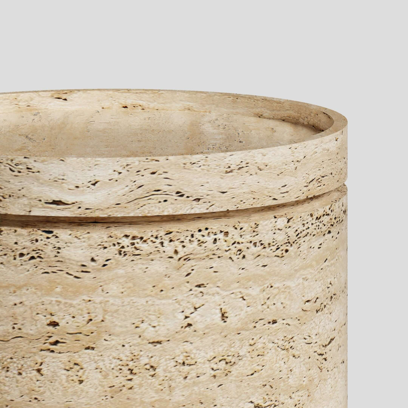 Close-up of Travertables Cycladic Secret Travertine End Table with storage, showcasing its cylindrical shape and textured surface. Made from natural light travertine, it features typical patterns and pores, along with a slightly rounded top edge against a light gray backdrop.