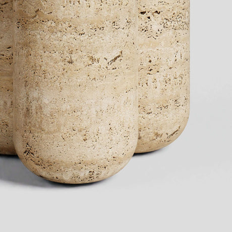 Close-up of two large, cylindrical stone pillars resembling the Travertable Travertine Elegance Accent Table, with a textured surface and natural beige and brown patterns, set against a plain gray background.