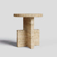 The Travertable Travertine Scepter Side Table features a unique architectural design in honed travertine with a round top and cross-shaped base. Its natural stone texture makes it an ideal centerpiece for modern coffee tables, set against a plain light gray background.
