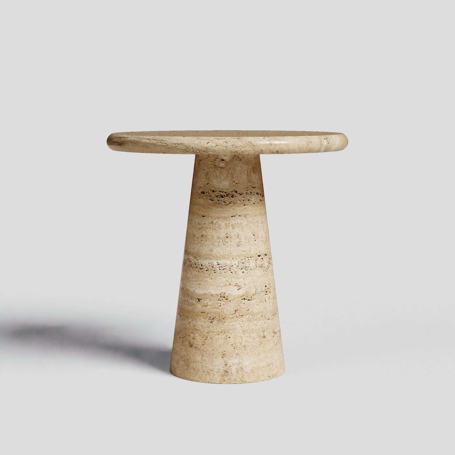 Set against a plain gray background, the Tavolino Pietra Travertine Column Table by Travertable showcases a classic European-inspired design with a round top and conical base, handcrafted from natural stone.
