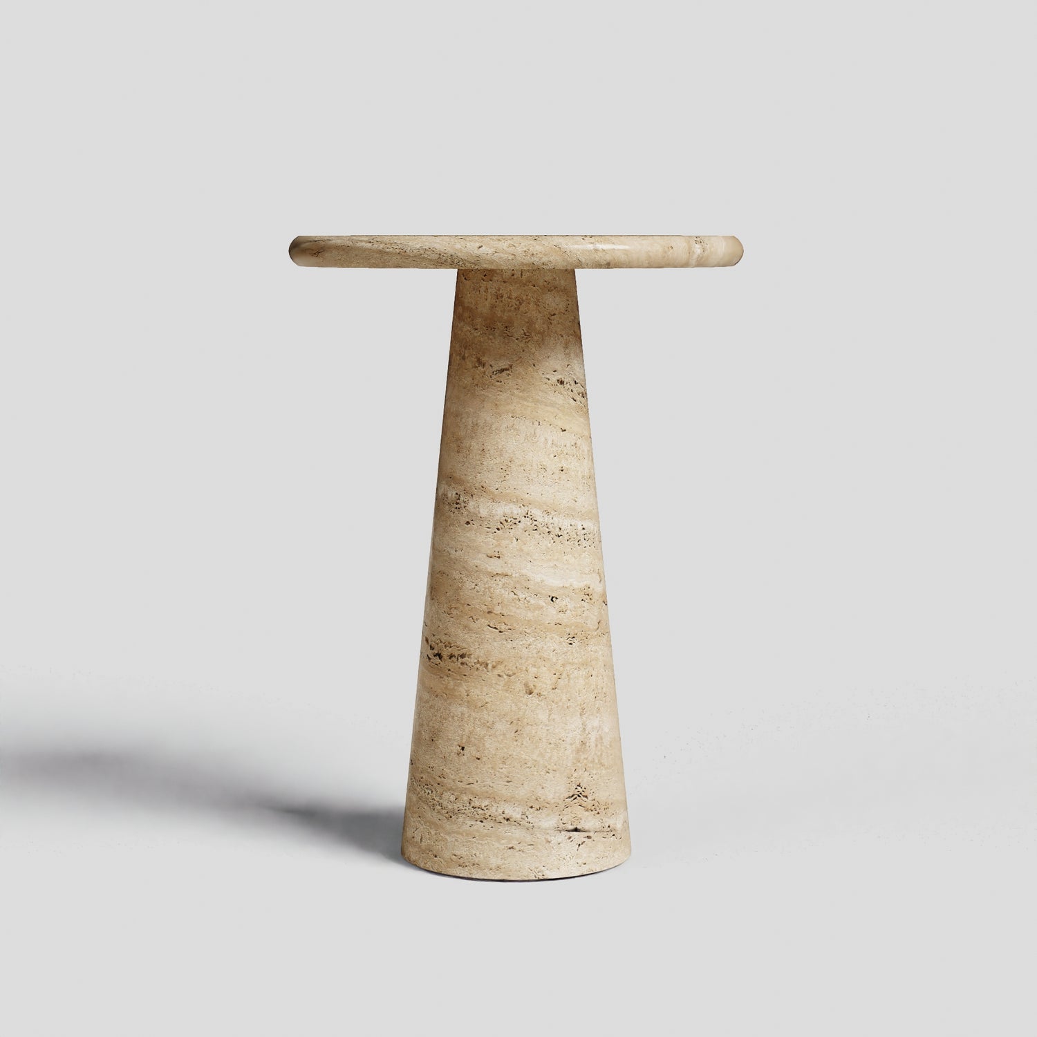 The Travertable Tavolino Pietra is a beige, cylindrical side table with a round top and tapered base, handcrafted from natural stone, standing elegantly against a light gray background.