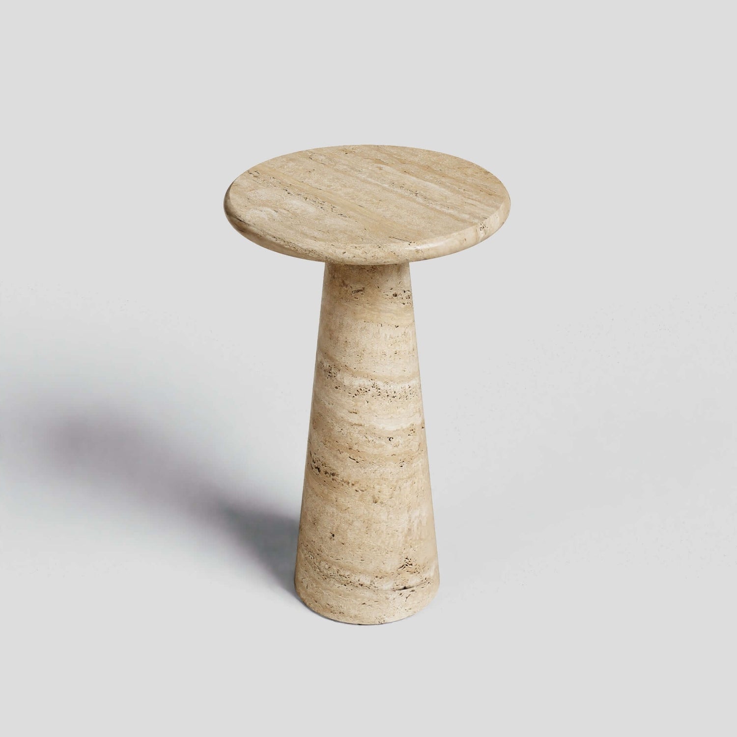 The Tavolino Pietra by Travertable is a tall, conical travertine column table with a round flat top, handcrafted from natural stone and set against a plain white background.