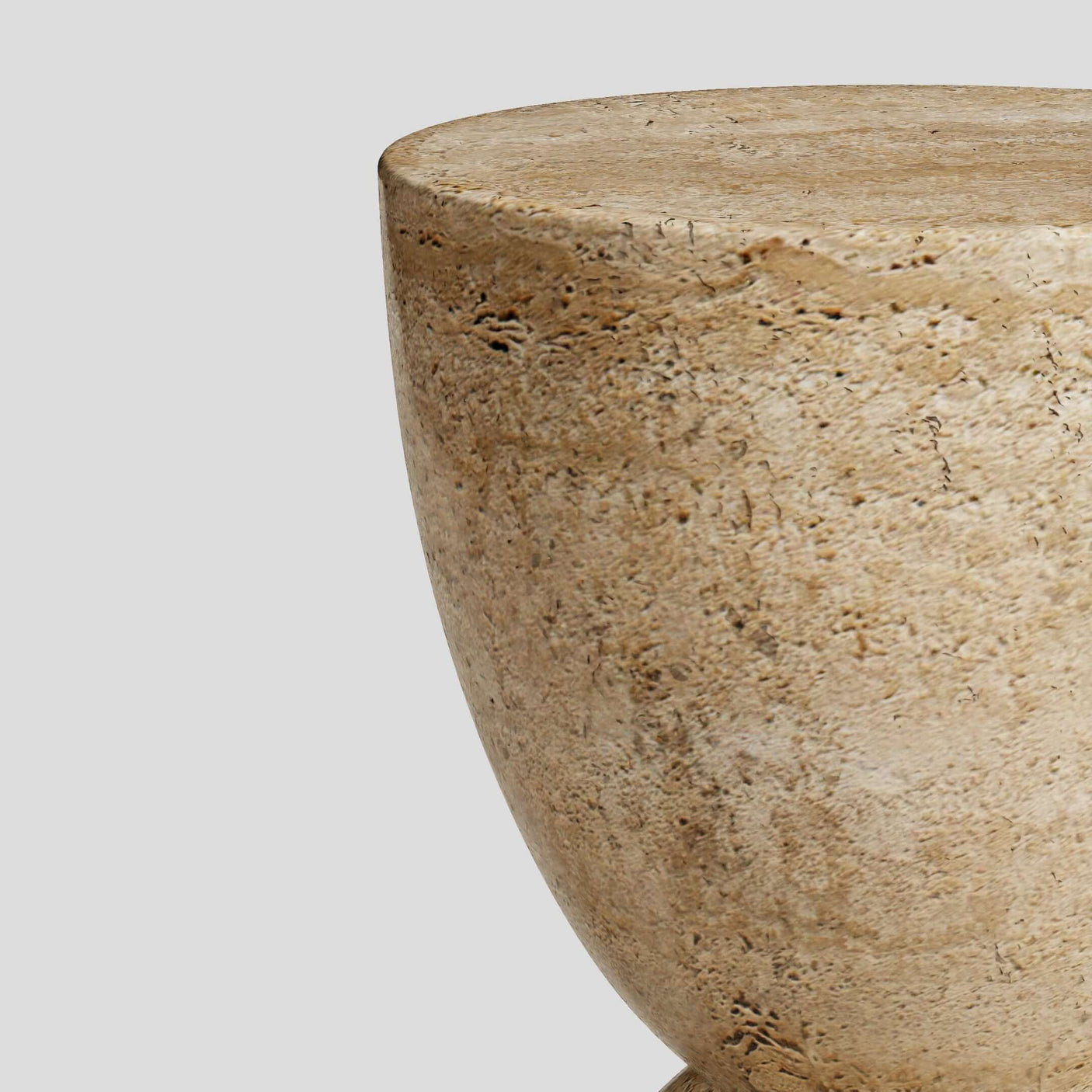 A close-up of the beige, rounded top half of the Eda Beige Travertine Sphere Table by Travertable. The elegant, minimalist solid stone piece sits against a plain gray background, showcasing its travertine-inspired design.