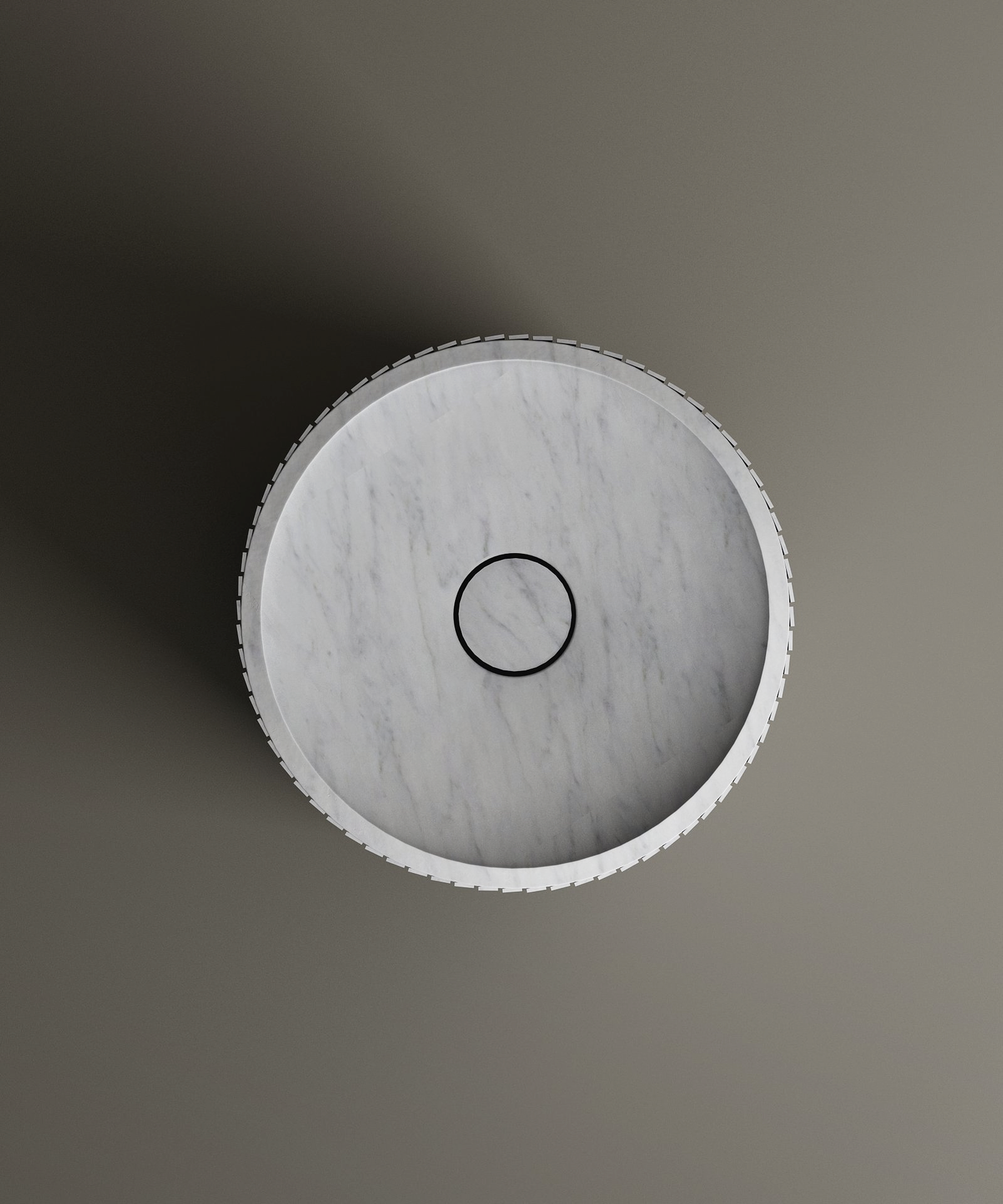 The TRAVERTABLE Carrara Round Fluted Marble Pedestal Vanity Sink is displayed from above, showcasing its smooth surface, black circular drain, and elegant fluted design against a plain gray background.