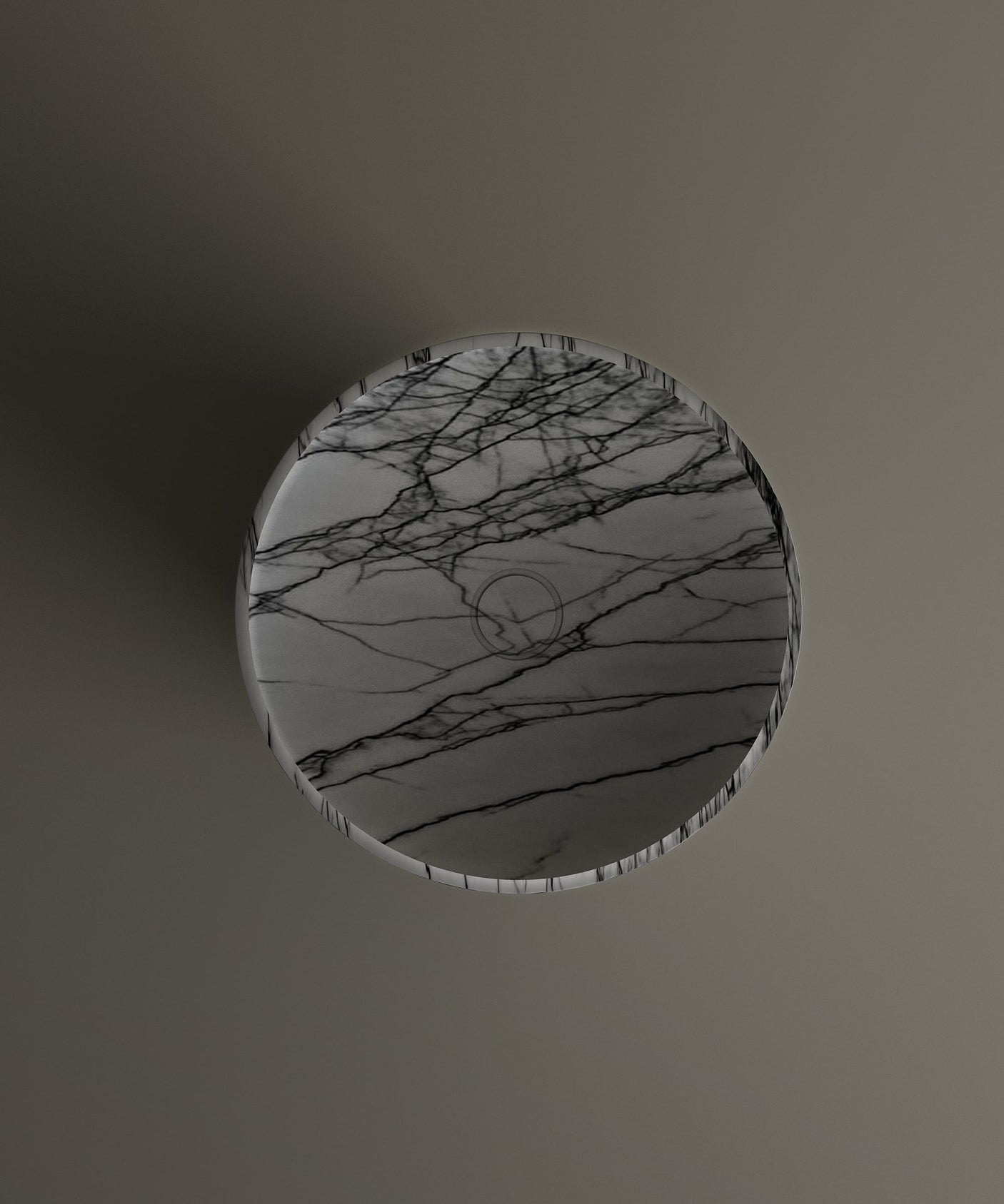 The TRAVERTABLE Lilac Marble Cylinder Pedestal Vanity Sink features a round, flat surface with striking gray marble pattern and dramatic veining, set against a plain gray background with a faint circular logo at its center.